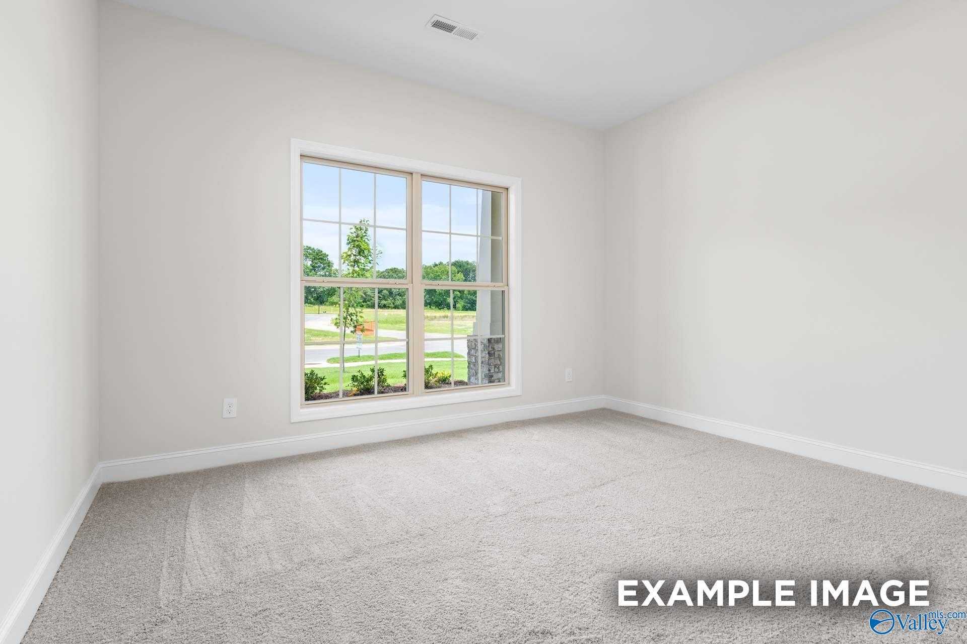 Bright empty bedroom with large window overlooking green yard in Davidson Homes The Daphne D, Arab, Alabama
