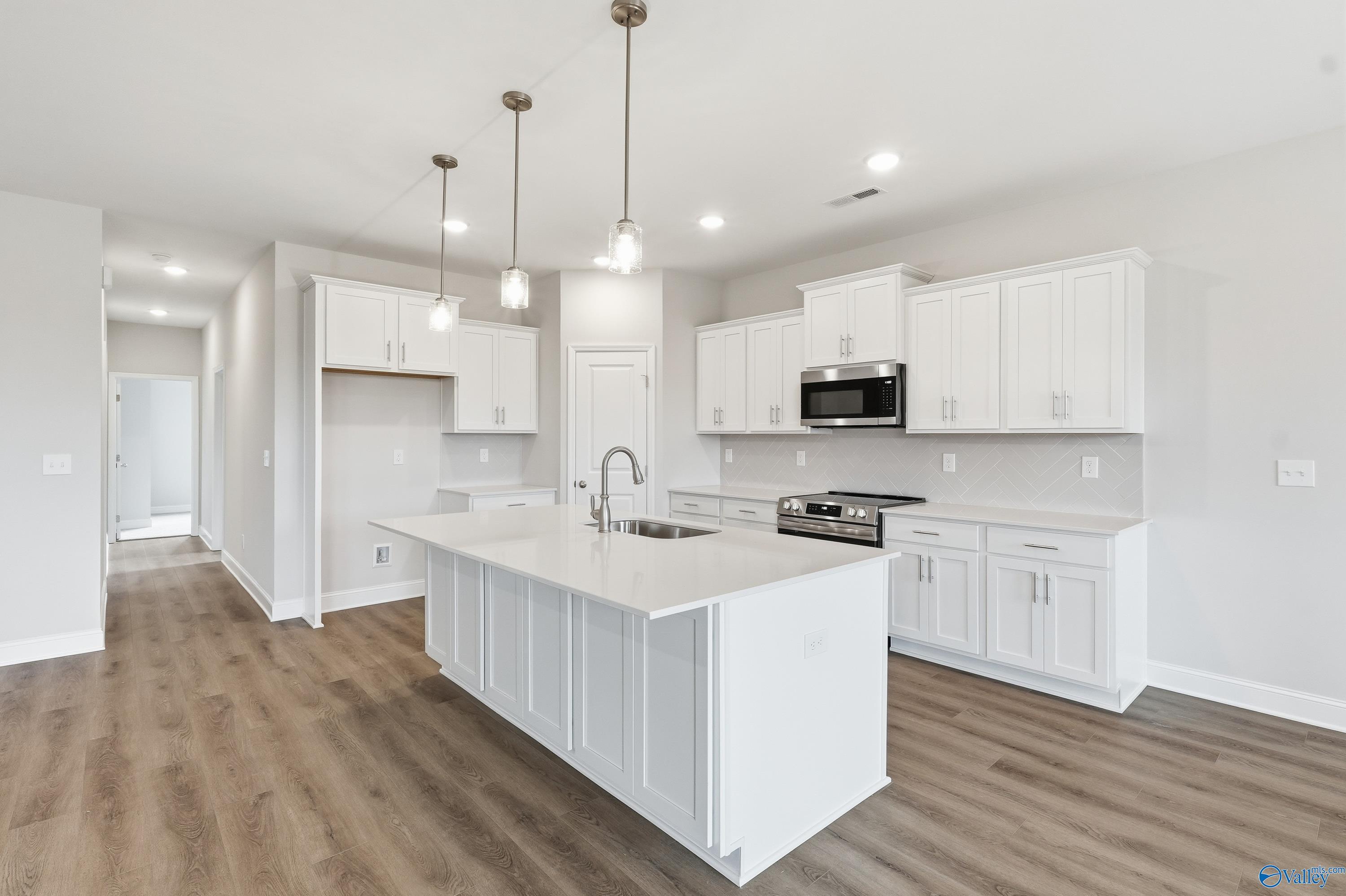 Modern white shaker kitchen with quartz island, gas cooktop, stainless appliances in The Rockford floor plan by Davidson Homes, Meridianville