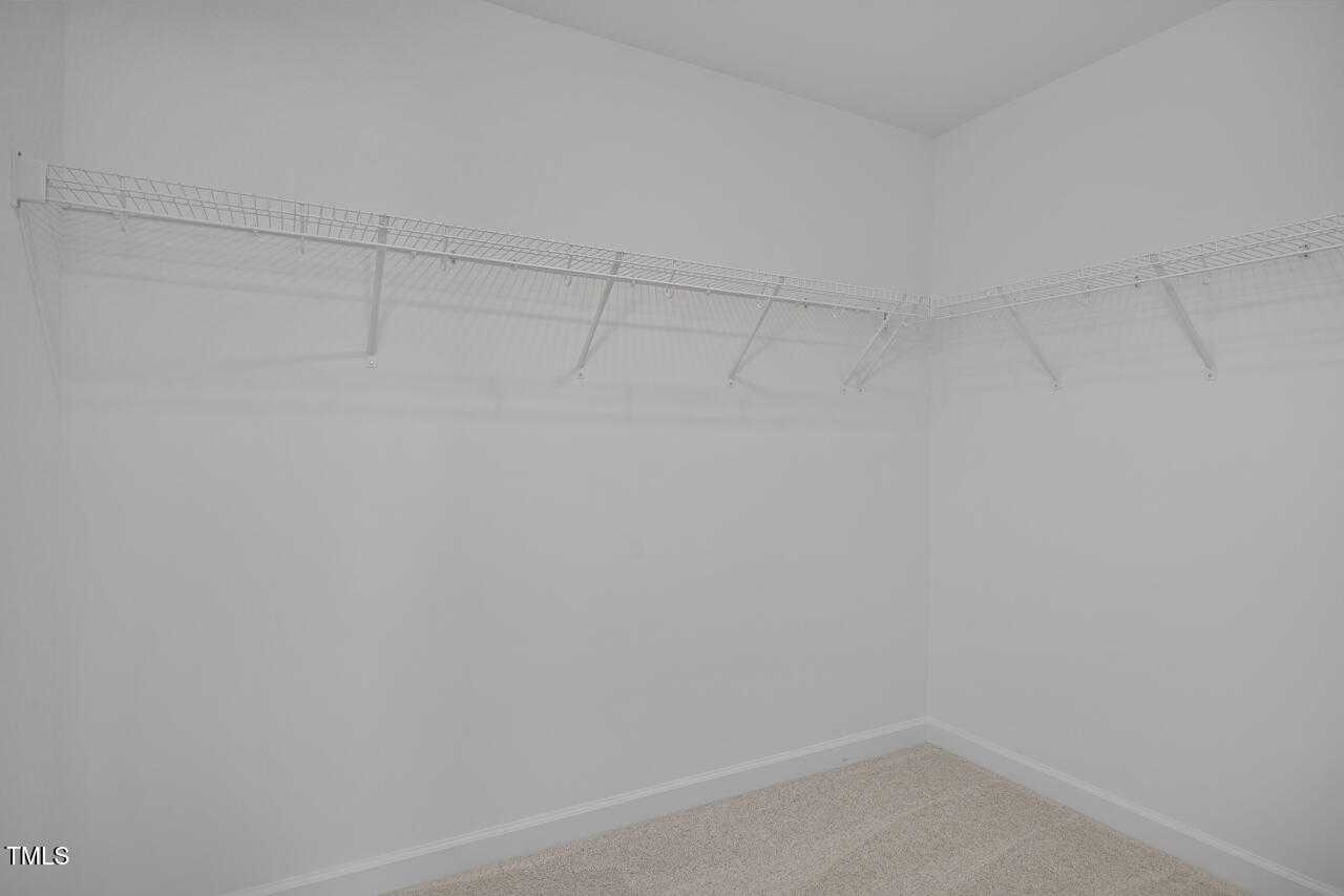 Spacious walk-in closet with white wire shelving in master suite of 3-bedroom Davidson Homes The Graham, Fuquay-Varina, NC