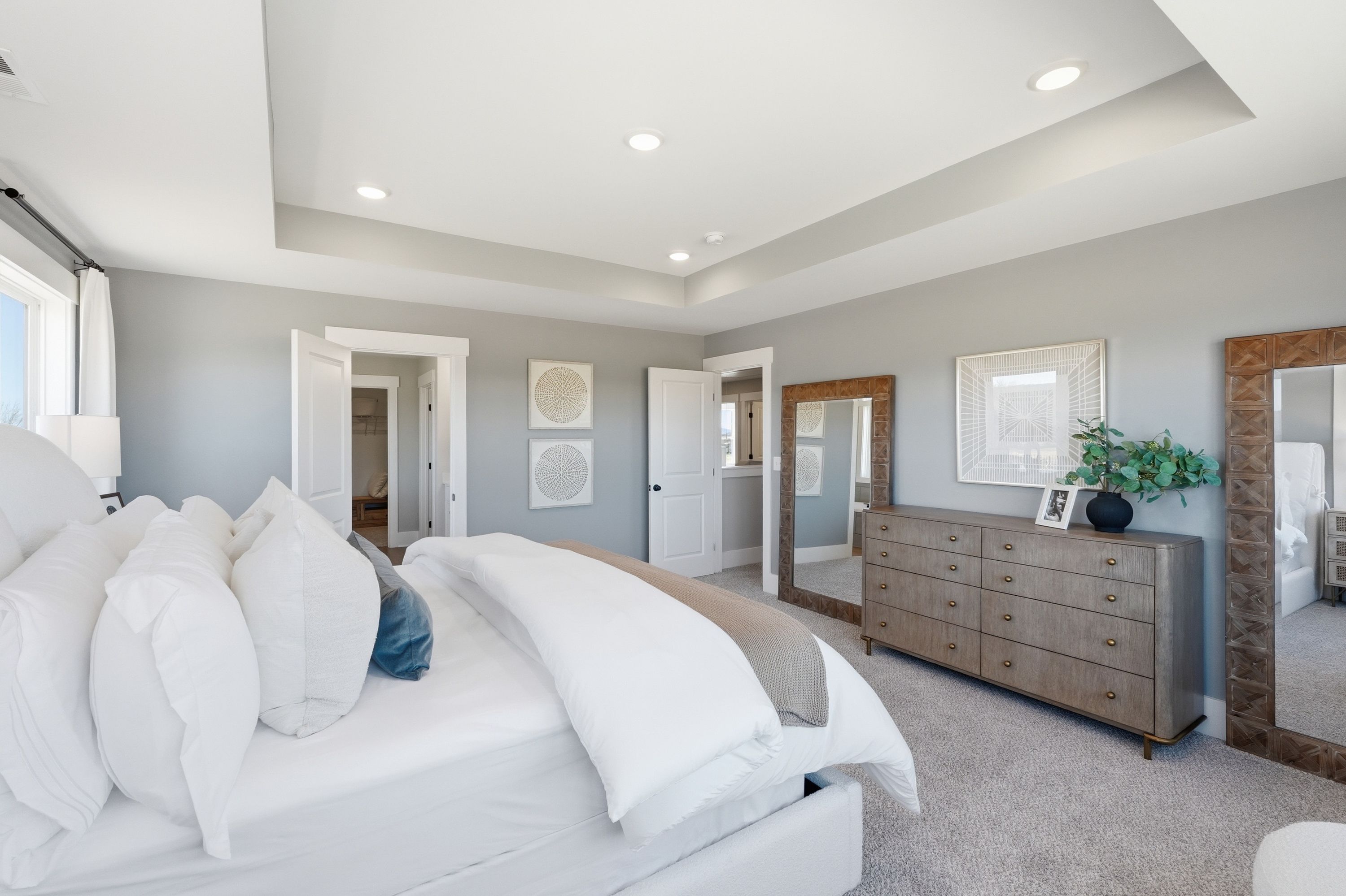 Spacious master bedroom in Berry Cove, New Market AL featuring gray walls, king bed with white duvet, wooden dresser, and mirrors