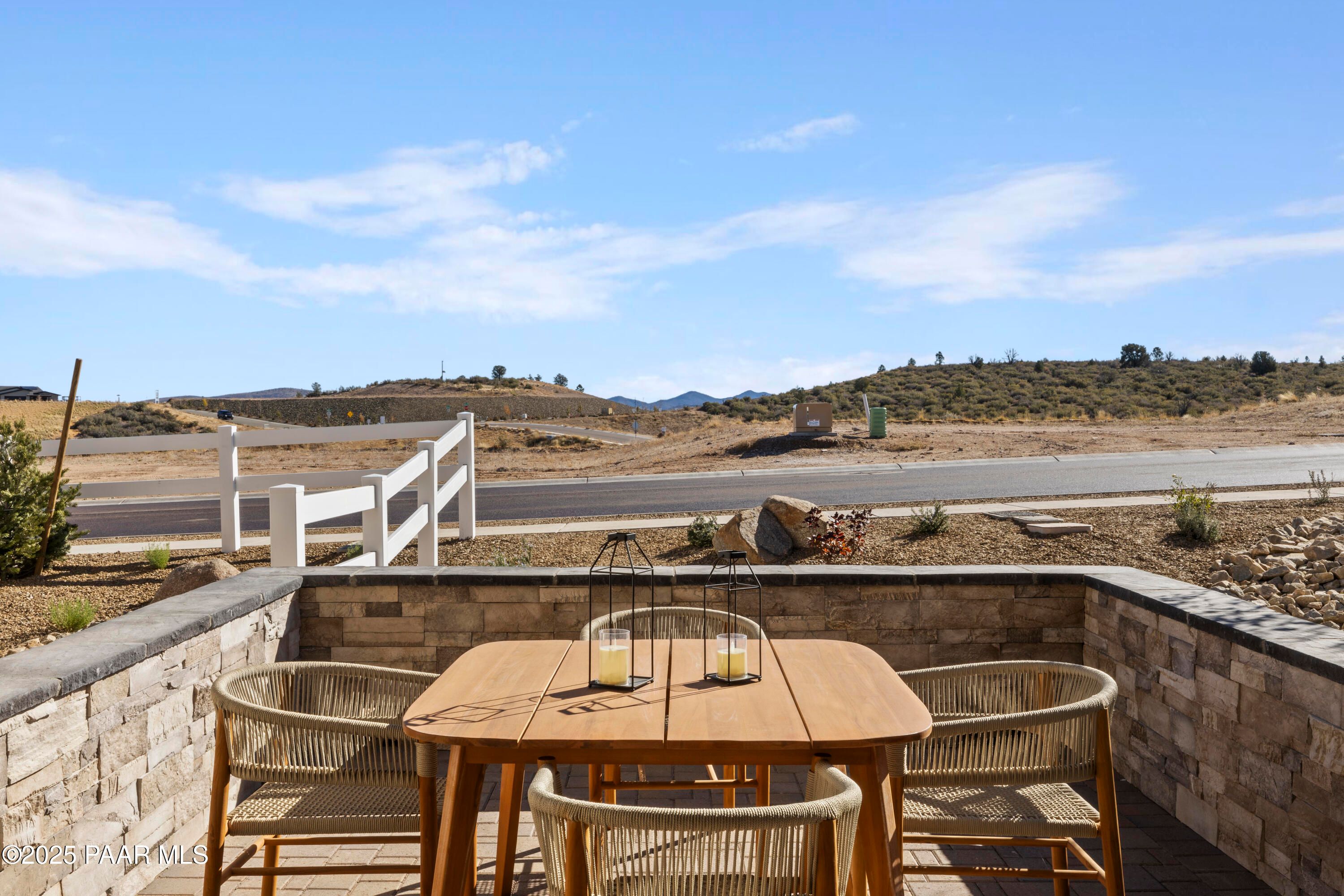 Covered back patio with teak table, rattan chairs, and desert hill views in Davidson Homes The Blaze D, Prescott Arizona