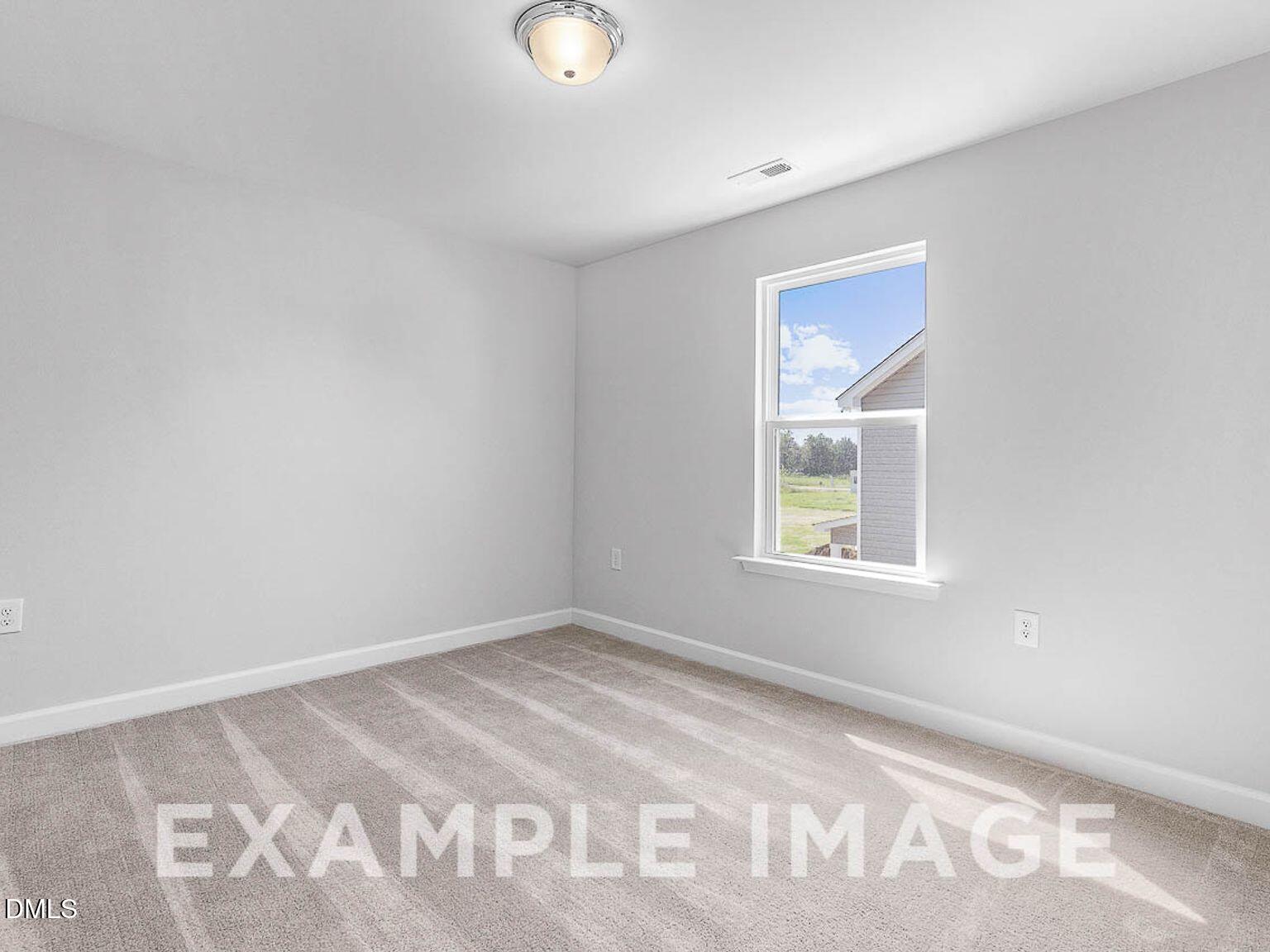 Bright empty bedroom with large window overlooking yard in Davidson Homes The Chestnut B, Lillington NC