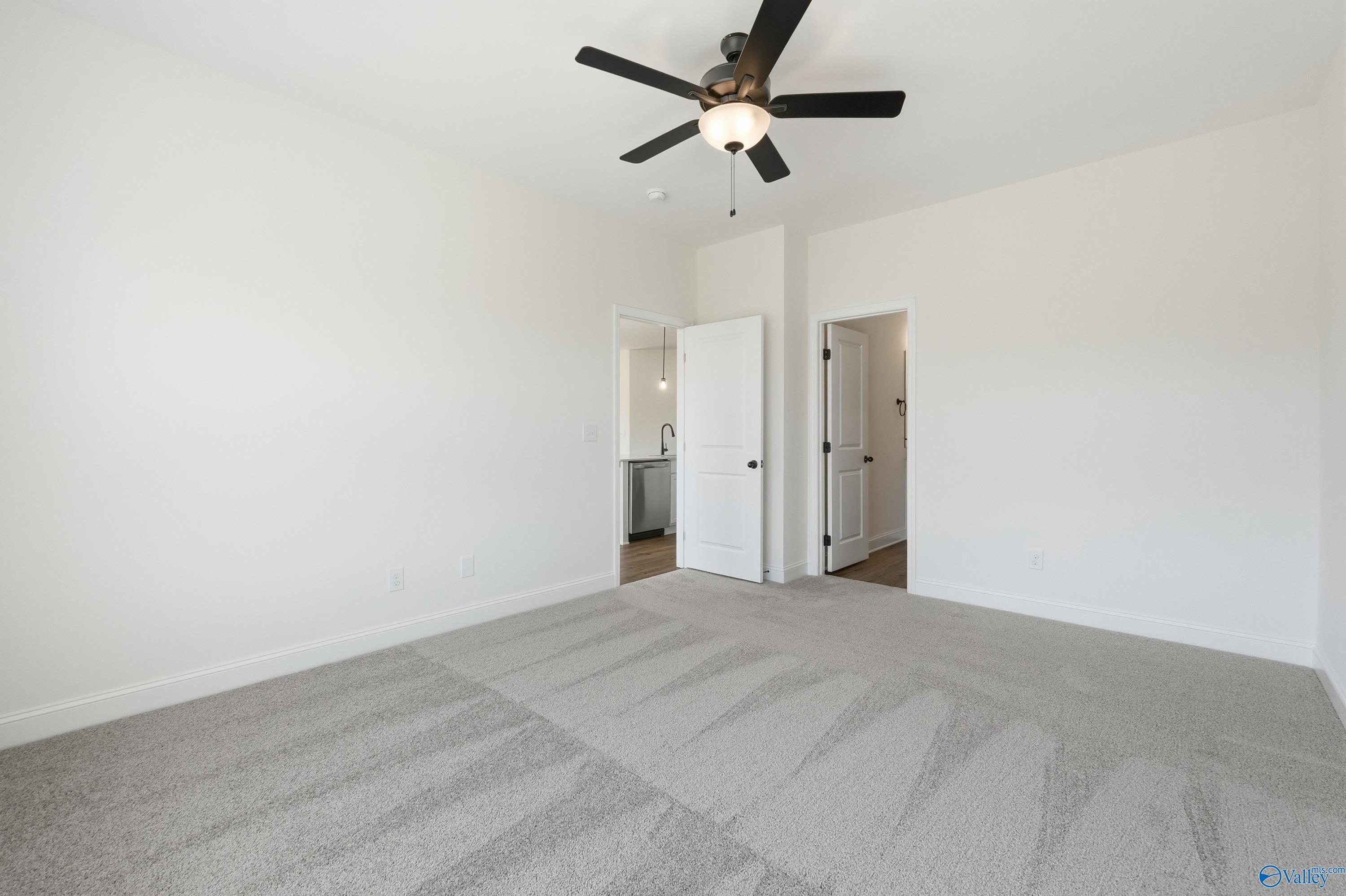 Spacious bedroom with gray carpet, ceiling fan, and bathroom access in Davidson Homes The Franklin C, New Market, Alabama