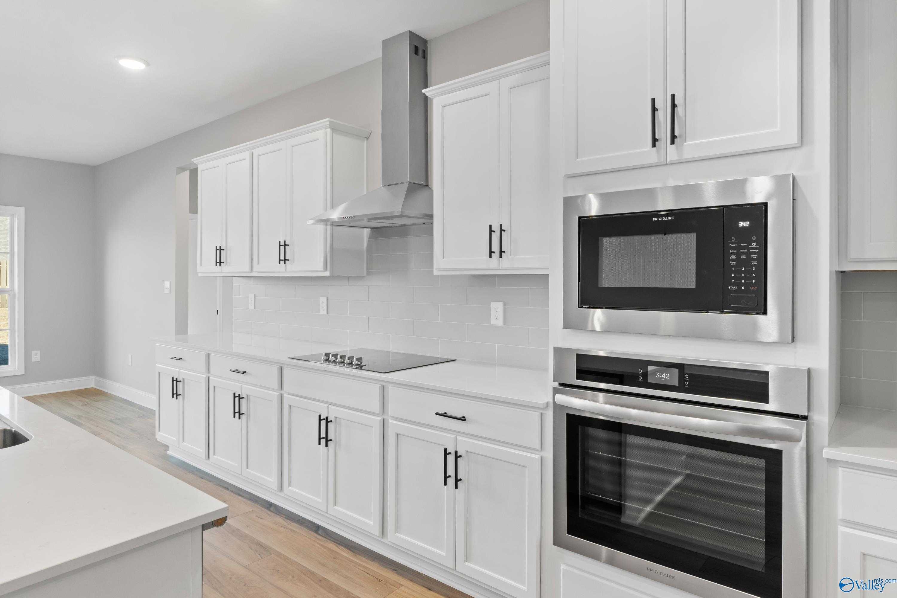 Modern white shaker kitchen with stainless steel microwave, oven, and island in Davidson Homes The Valencia, Meridianville, AL