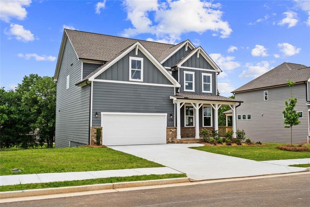 Two-story gray Craftsman home with covered front porch, two-car garage, and manicured lawn in Wehunt Meadows, Hoschton, Georgia