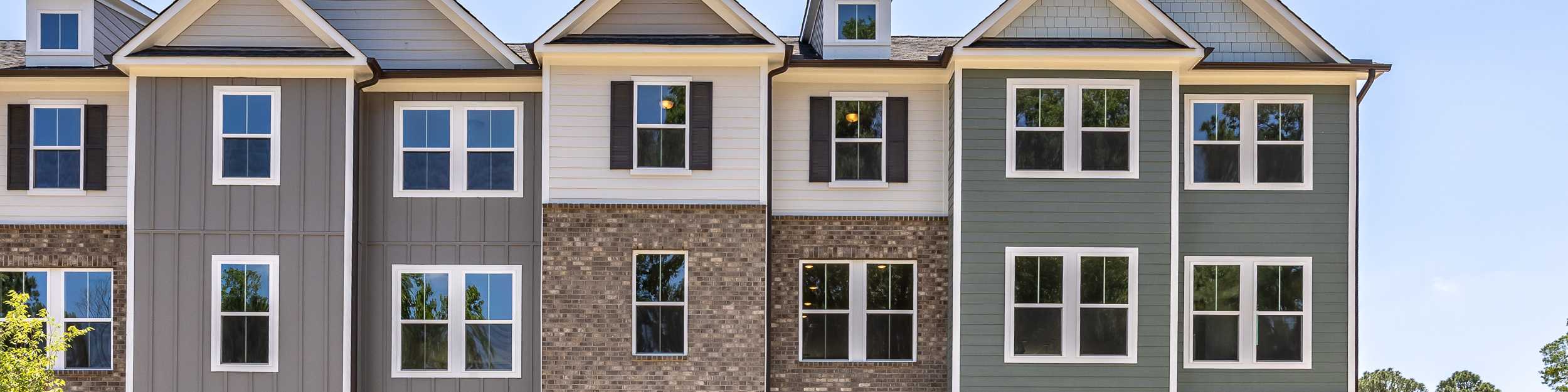 Three-story townhome exteriors at Forestville Yard in Knightdale, NC, featuring brick, siding, and modern architecture.