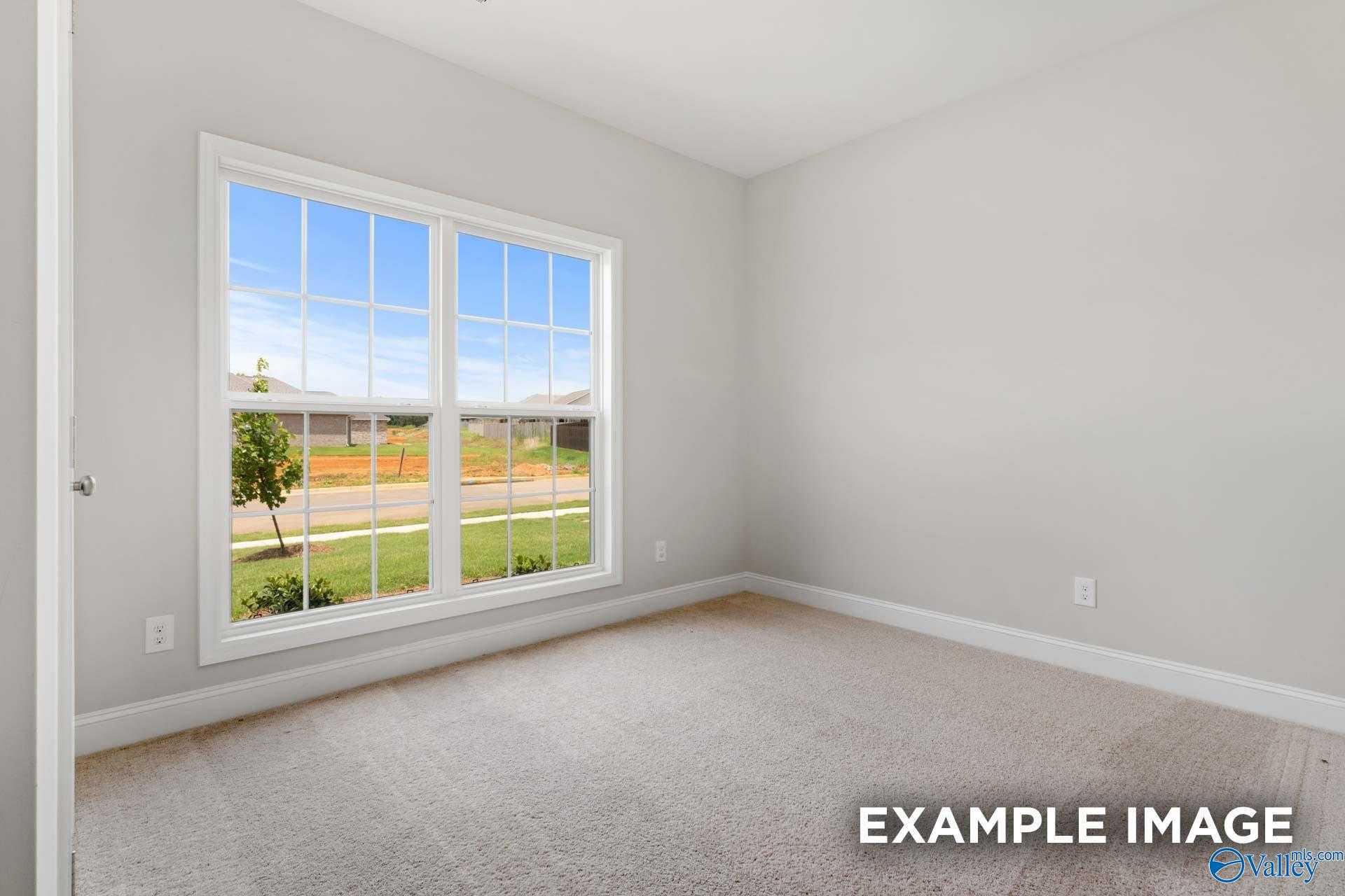Bright bedroom with large window overlooking lush green yard in Davidson Homes The Asheville C, Meridianville, Alabama