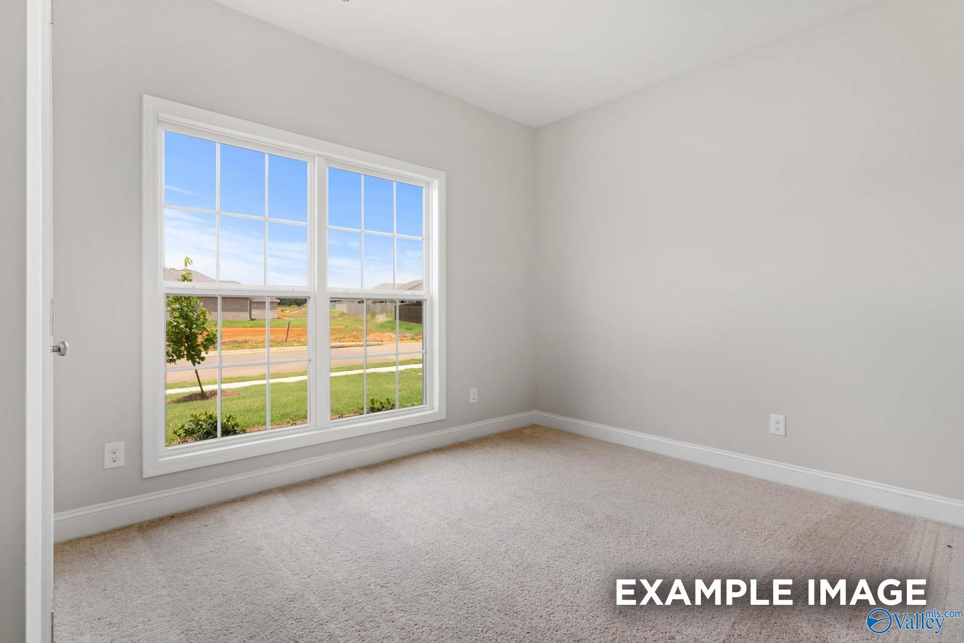 Bright bedroom with large window overlooking suburban neighborhood in The Asheville C by Davidson Homes, Meridianville, Alabama