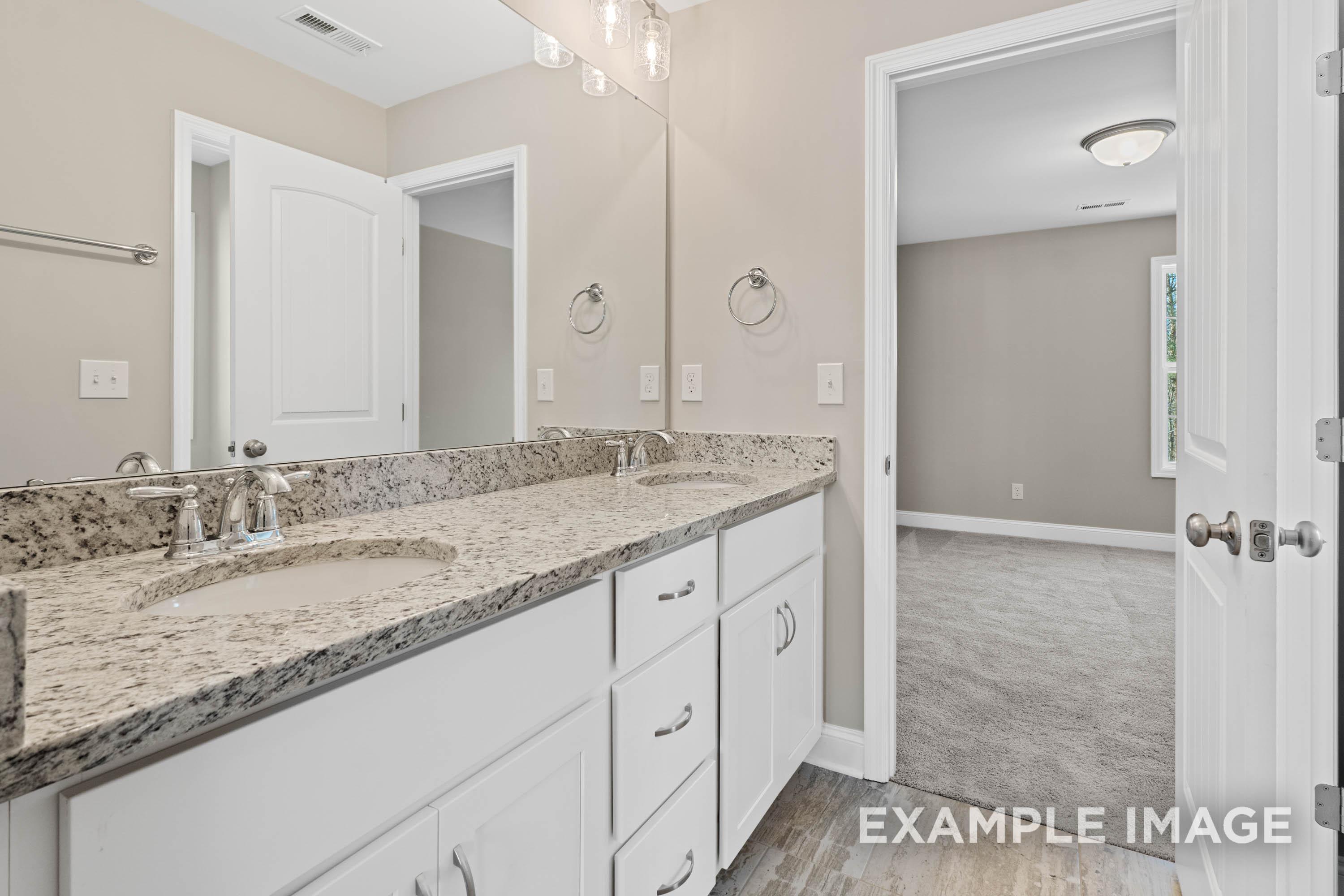 Spacious master bathroom in The Madison B with double vanity, granite counters, white cabinets, and neutral tones
