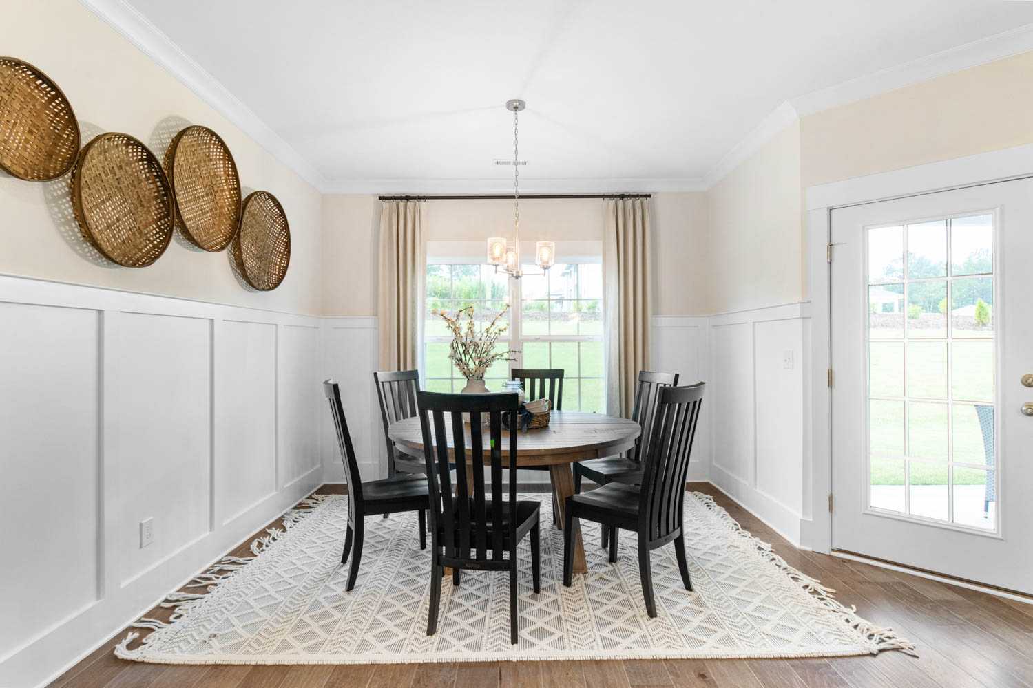 cozy dining area with white wall paneling and door to covered patio