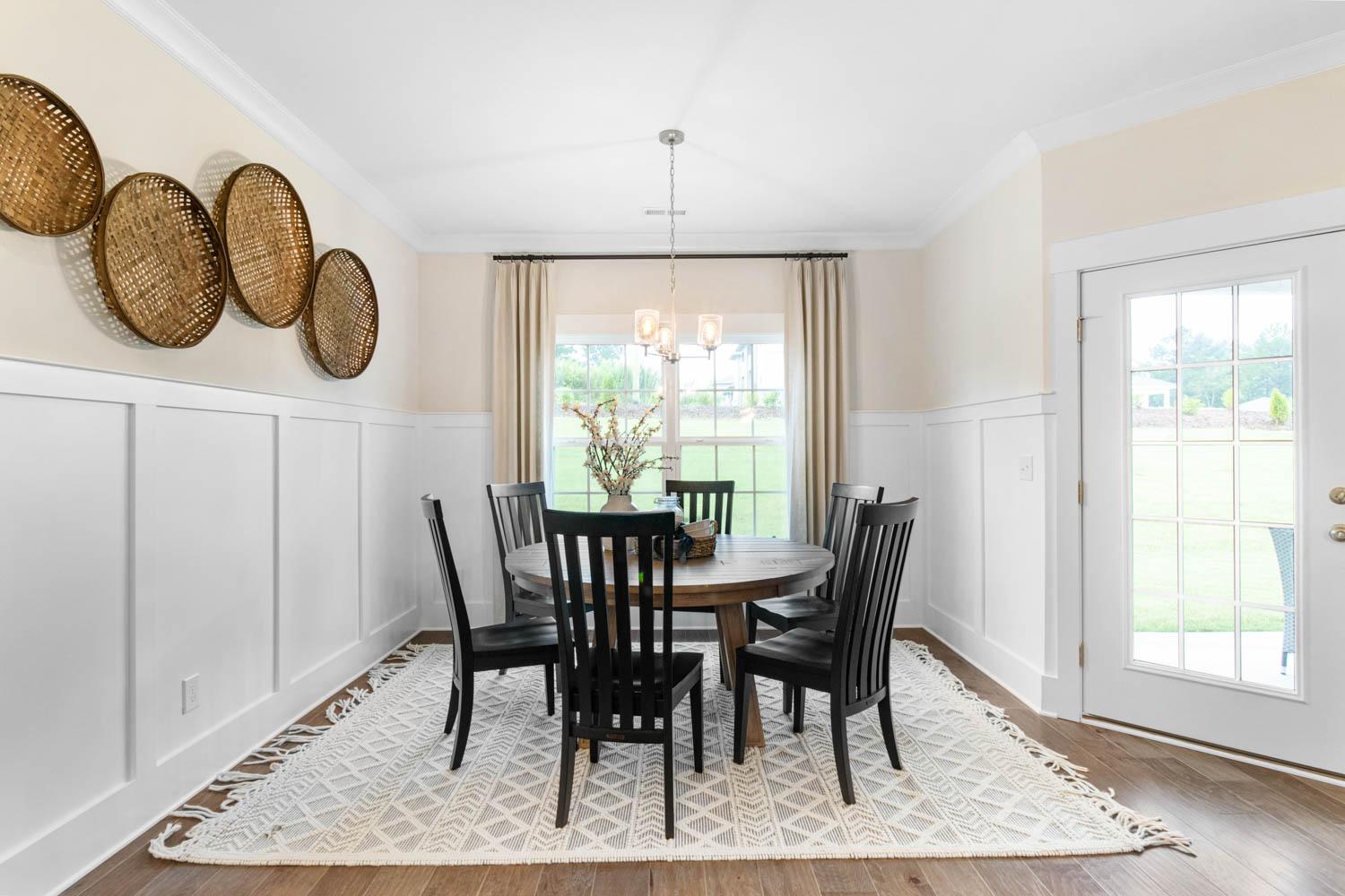 cozy dining area with white wall paneling and door to covered patio