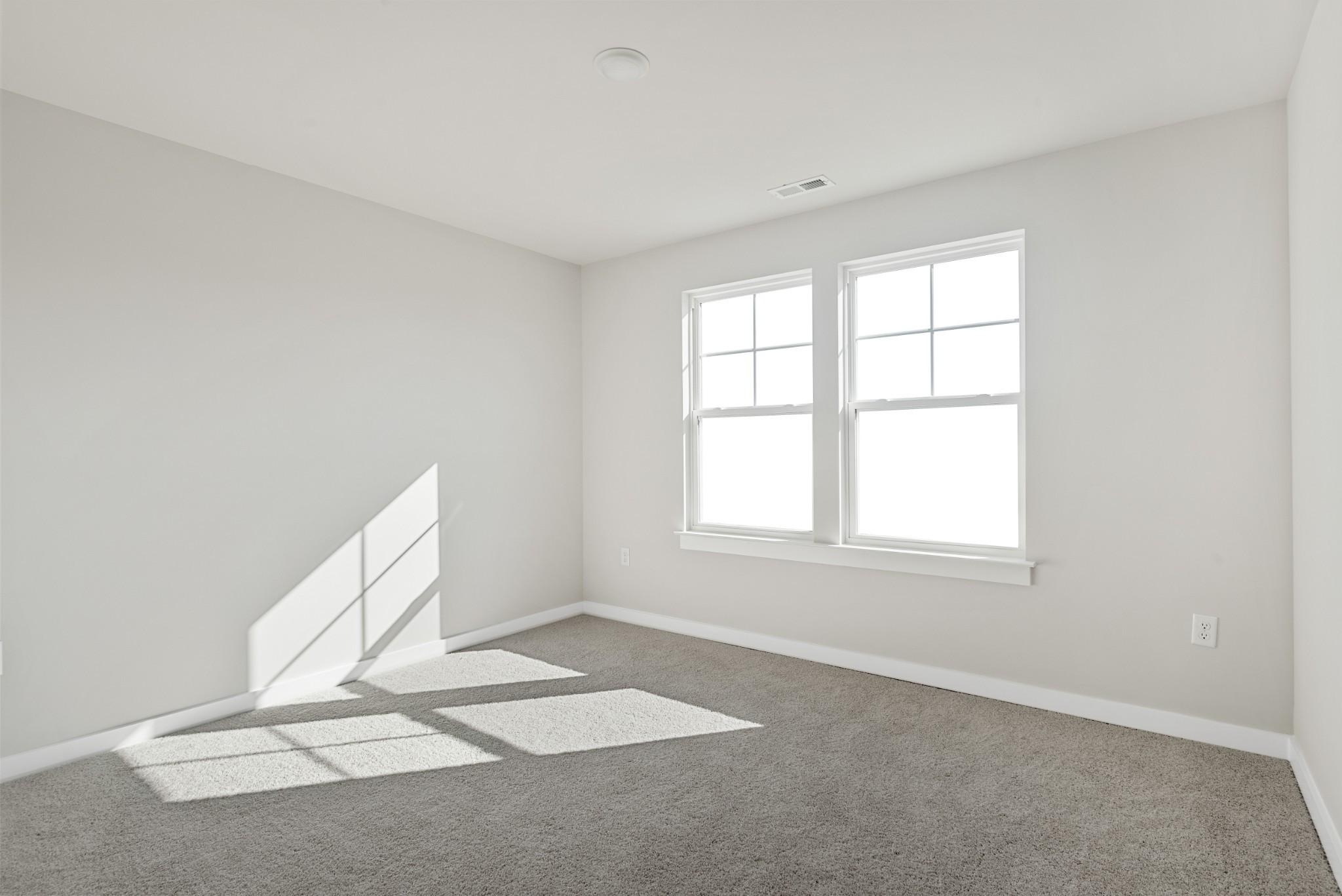 Bright secondary bedroom with gray carpet, neutral walls, and sunlit double windows in Davidson Homes The Willow B, White House, TN