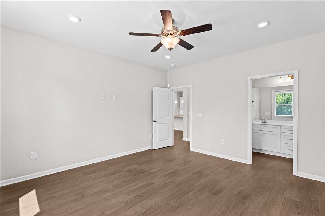 Bright master bedroom with ceiling fan, hardwood floors, and en-suite bathroom in The Orion 4-bedroom home, Cusseta, Alabama