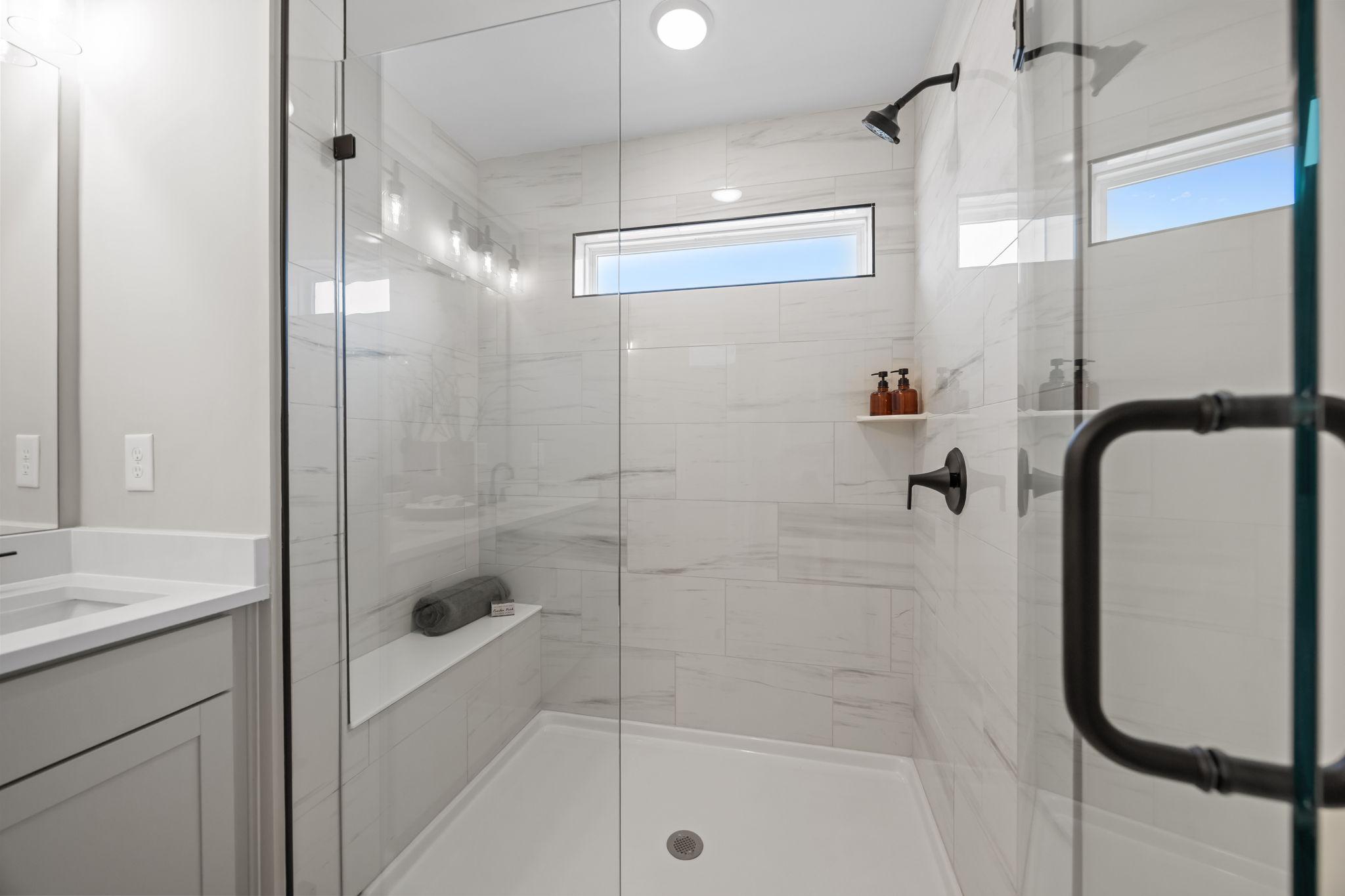 Spacious walk-in shower in Bradford Raleigh NC bathroom with frameless glass enclosure, white marble tiles, bench seat