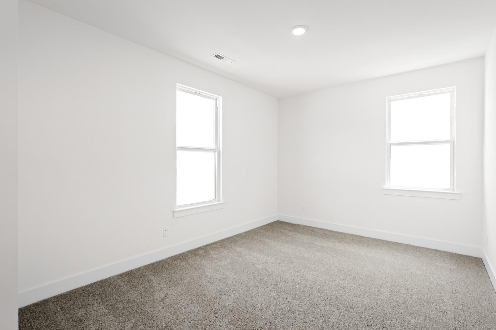 Bright bedroom with neutral carpet and dual windows in Davidson Homes The Cottonwood E plan, Woods Crossing, Gallatin, Tennessee
