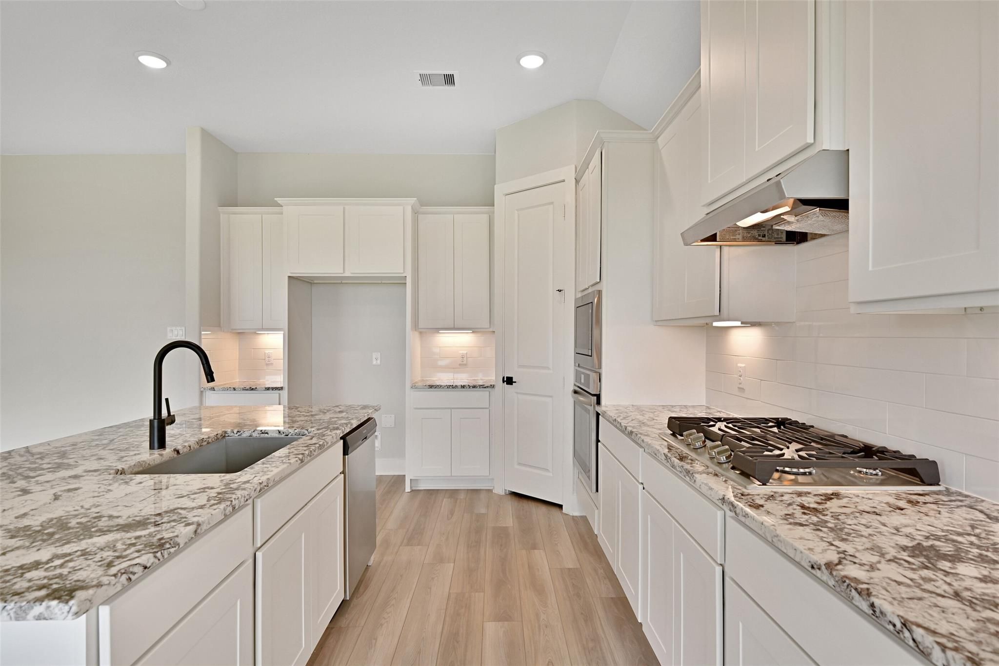 Modern white shaker kitchen with quartz island, gas range, stainless appliances in Davidson Homes Edward C, Lago Mar Texas City