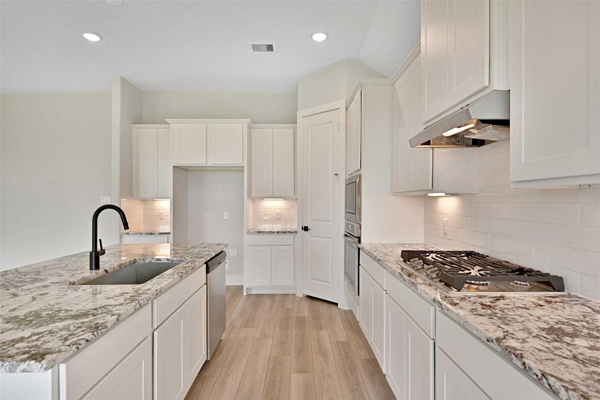 Modern white shaker kitchen with quartz island, gas range, stainless appliances in Davidson Homes Edward C, Lago Mar Texas City