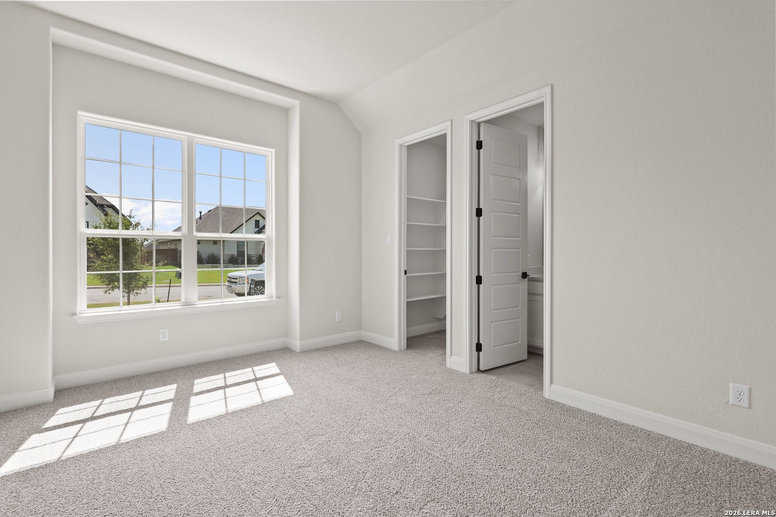 Bright bedroom with walk-in closet and en-suite bath in The Summerlin B floor plan at Potranco Oaks, Castroville, Texas.
