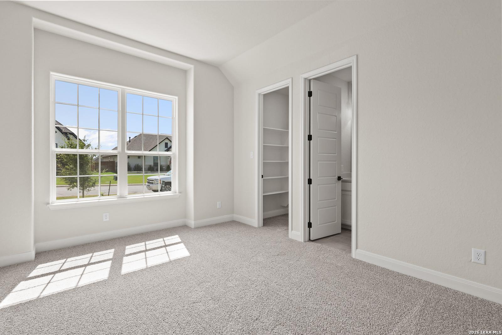 Bright bedroom with walk-in closet and en-suite bath in The Summerlin B floor plan at Potranco Oaks, Castroville, Texas.