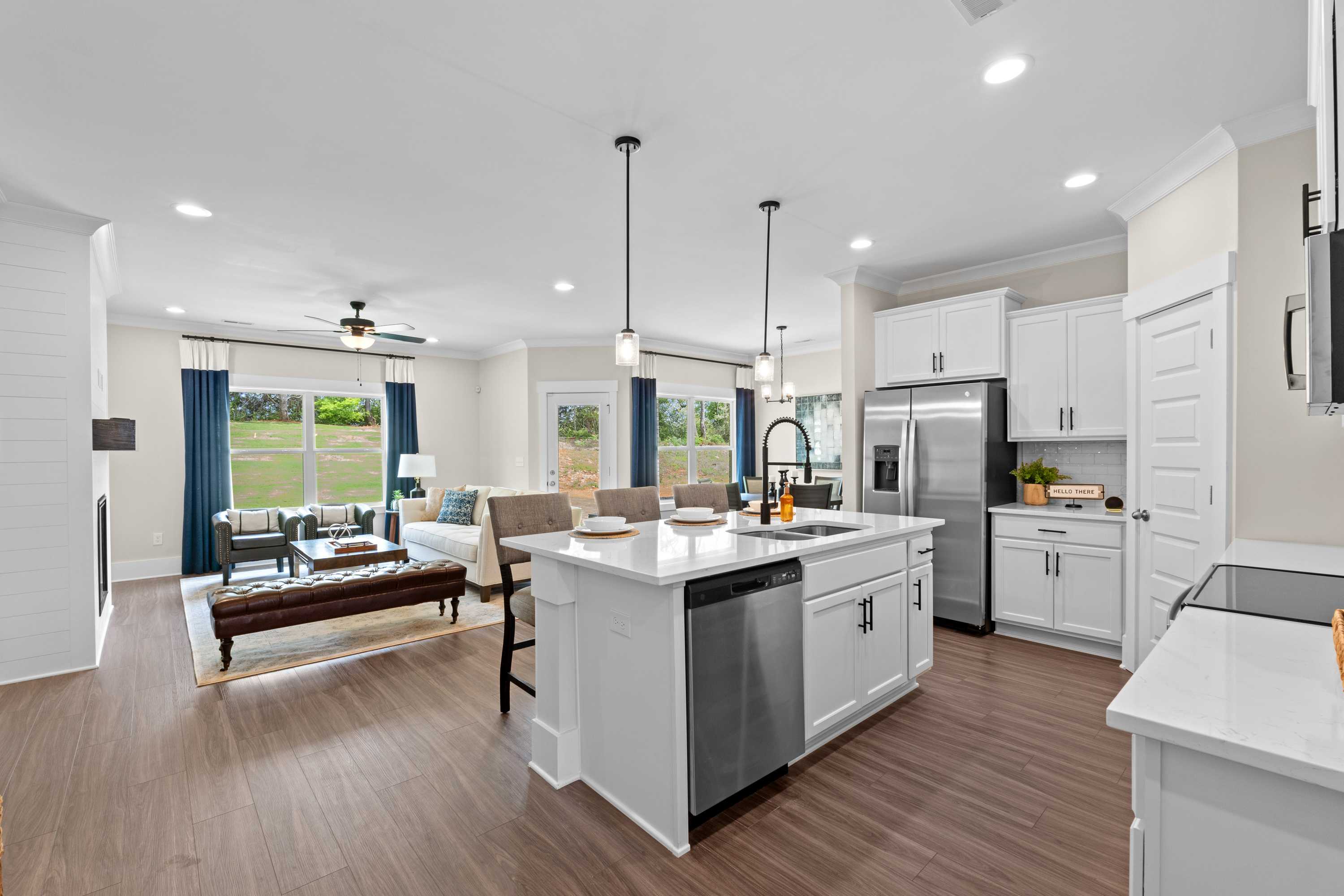 Spacious open-concept kitchen and living room at Ivy Hills in Toney Alabama with white cabinets, hardwood floors, and large windows
