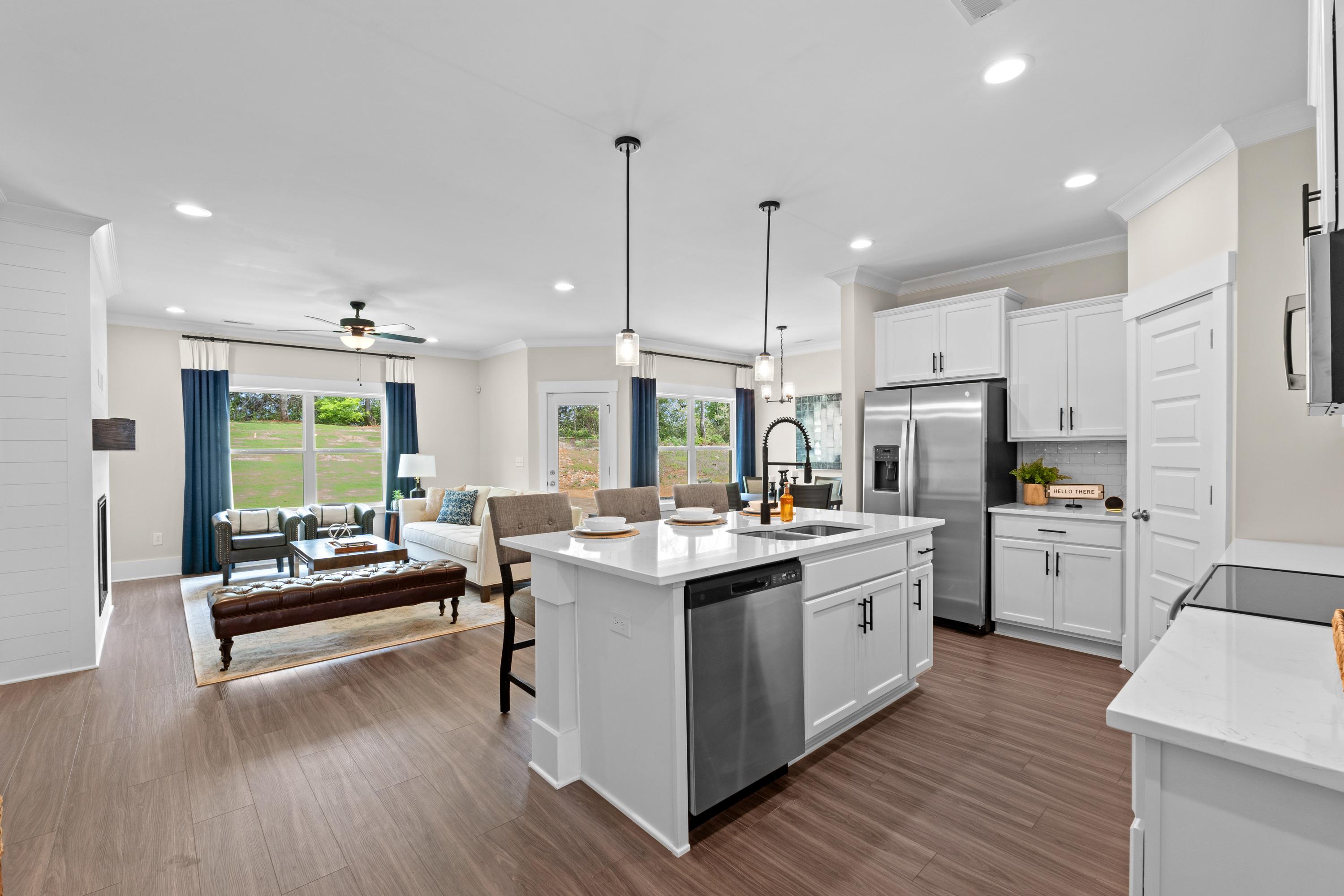 Spacious open-concept kitchen and living room at Ivy Hills in Toney Alabama with white cabinets, hardwood floors, and large windows