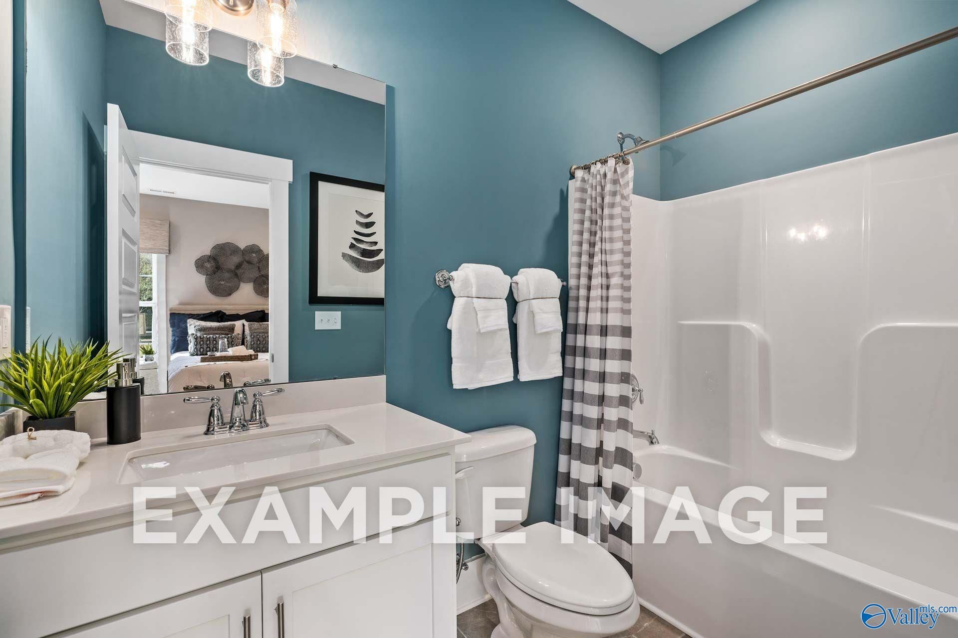 Bathroom with white vanity, mirror, and tub shower in Davidson Homes The Harrison floor plan at Cain Park, Hartselle, Alabama
