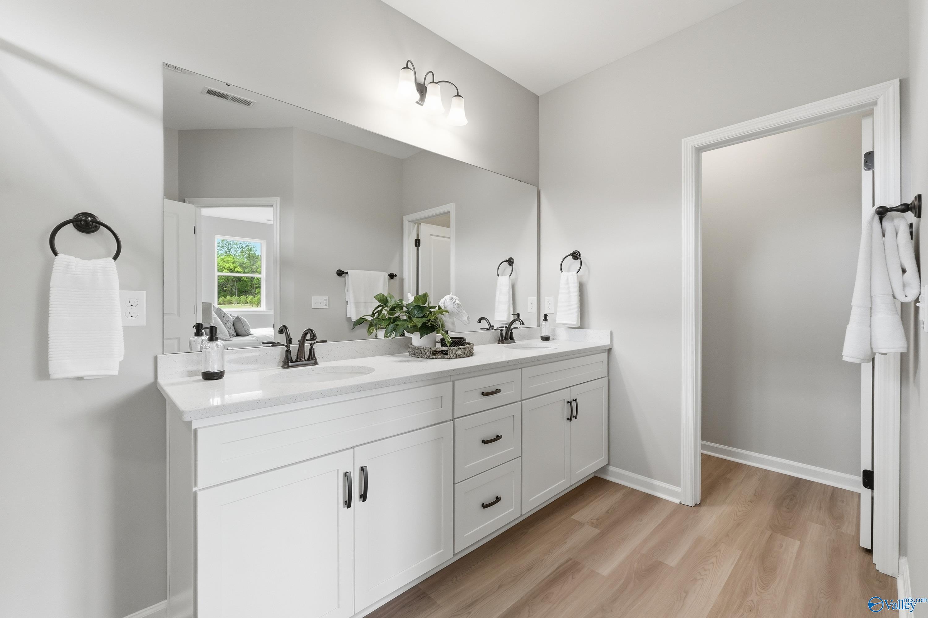 Elegant master bathroom double vanity with white shaker cabinets, quartz counters, and sconce lighting in Davidson Homes The Dorado, Huntsville