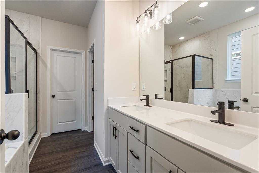 Modern master bathroom with double vanity, frameless glass shower, and wood flooring in Davidson Homes The Daphne B, Loganville GA