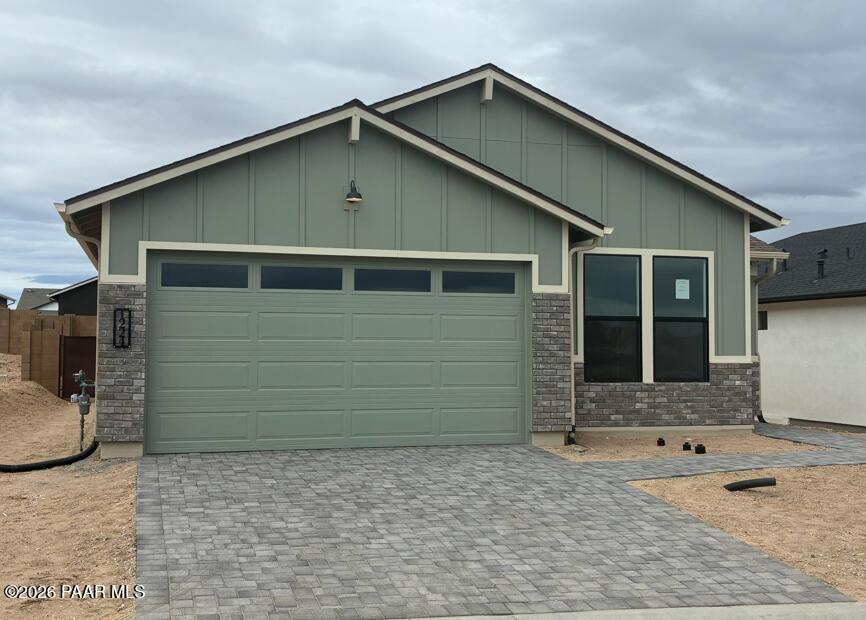 Sage green single-story home with 2-car garage, brick accents, paver driveway in South Ranch, Prescott, Arizona