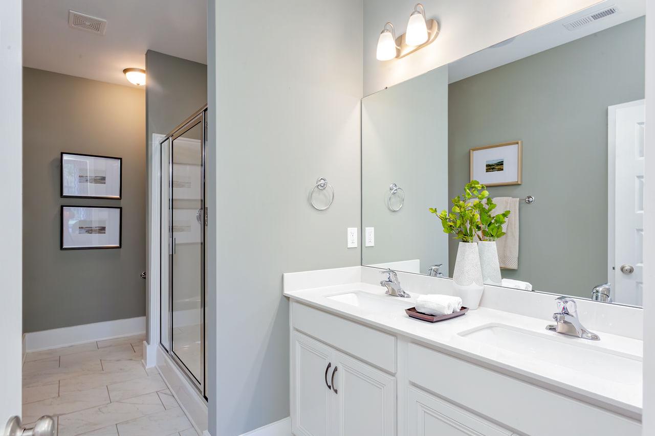 Modern primary bathroom at Williams Pointe in Huntsville AL with double vanity, gray walls, and frameless glass shower