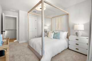Spacious master bedroom in The Washington H townhome with white canopy bed, neutral tones, and balcony railing