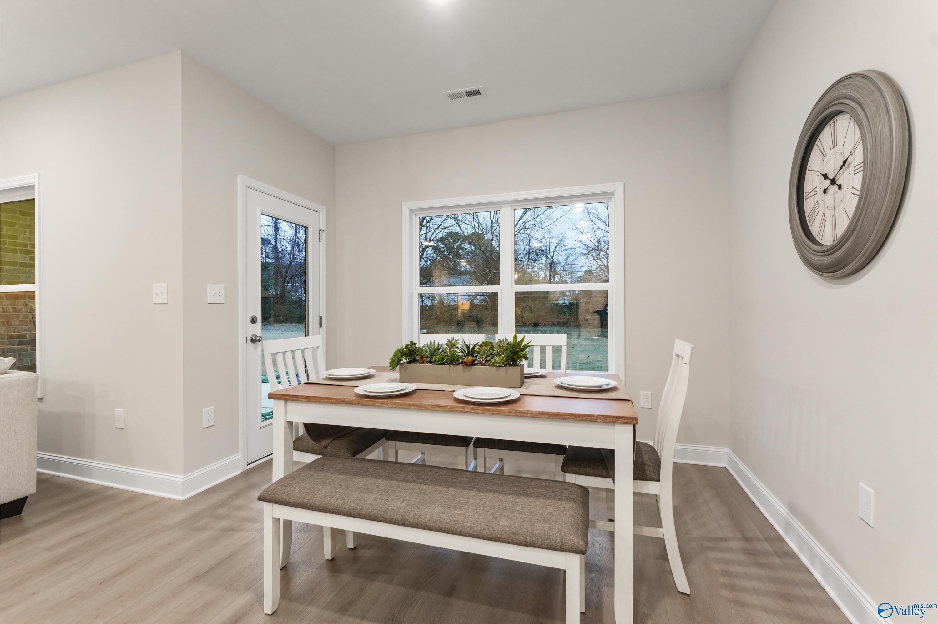 Bright dining room with wooden table, white chairs, bench, and large windows in Davidson Homes The Asheville C, Huntsville, Alabama