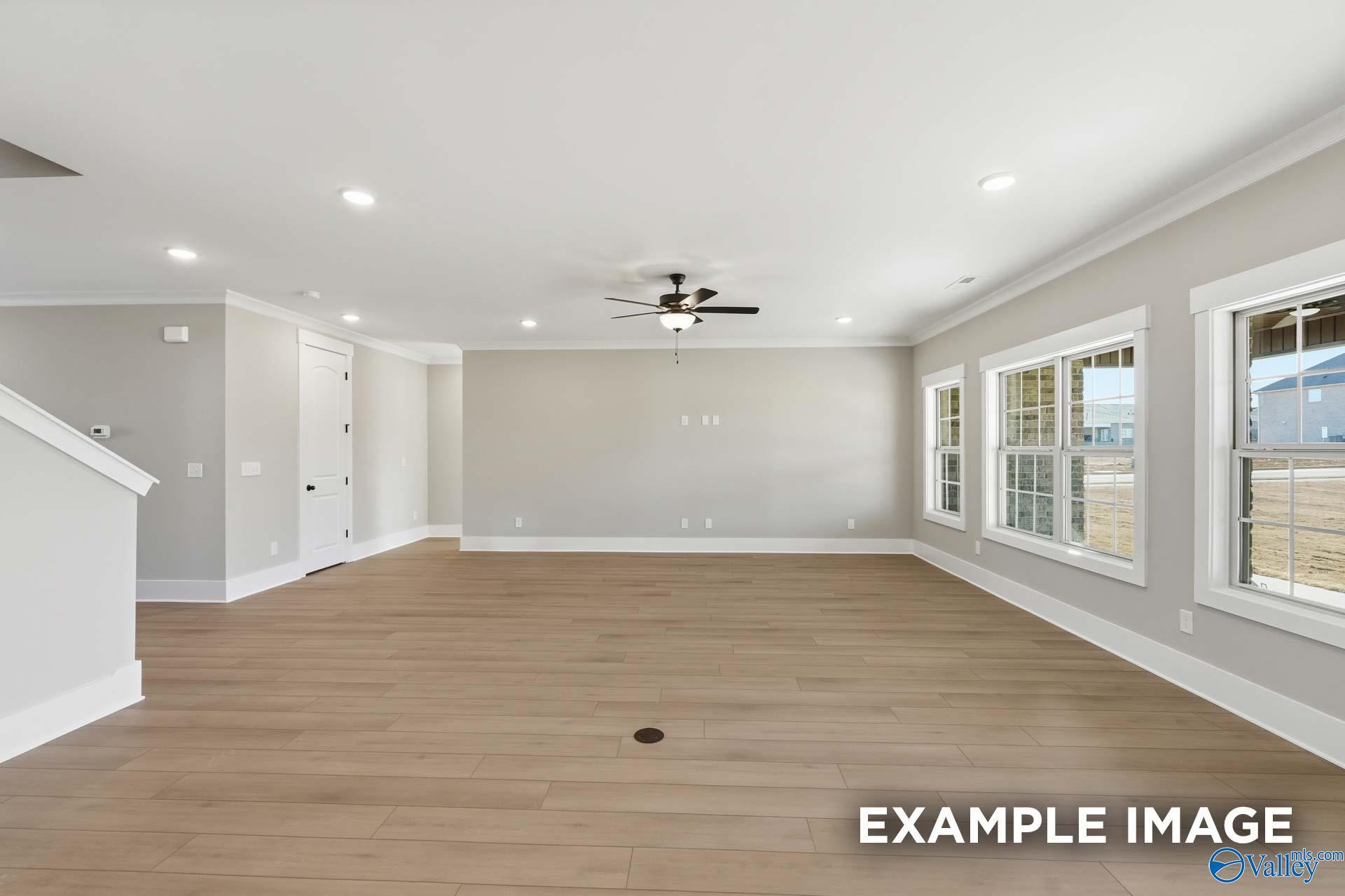 Spacious great room with light hardwood floors, large windows, ceiling fan in Davidson Homes The Emory, Decatur AL