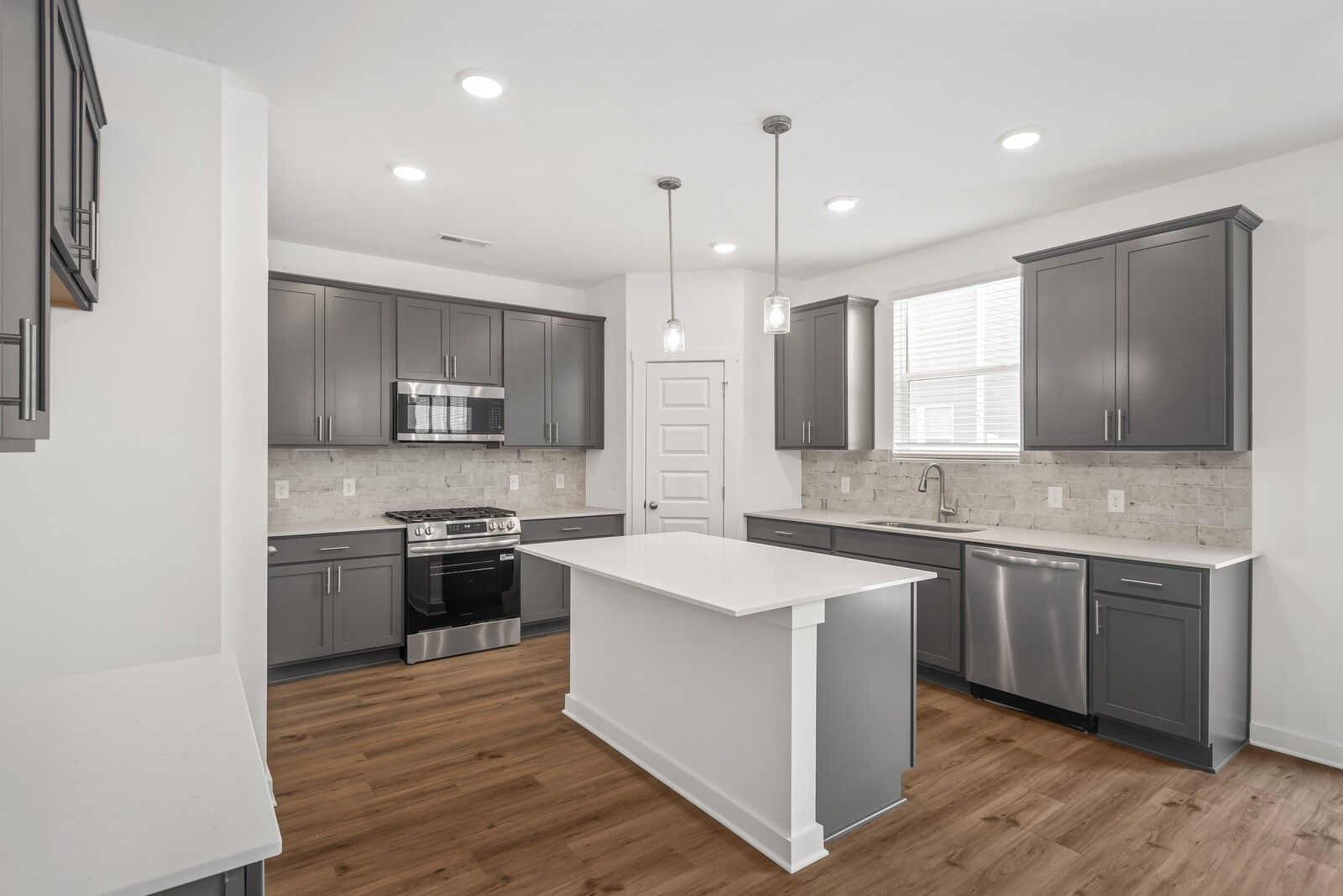 Modern gray kitchen with white island, stainless appliances, subway tile backsplash in Davidson Homes The Gordon C, Sage Farms, White House, TN