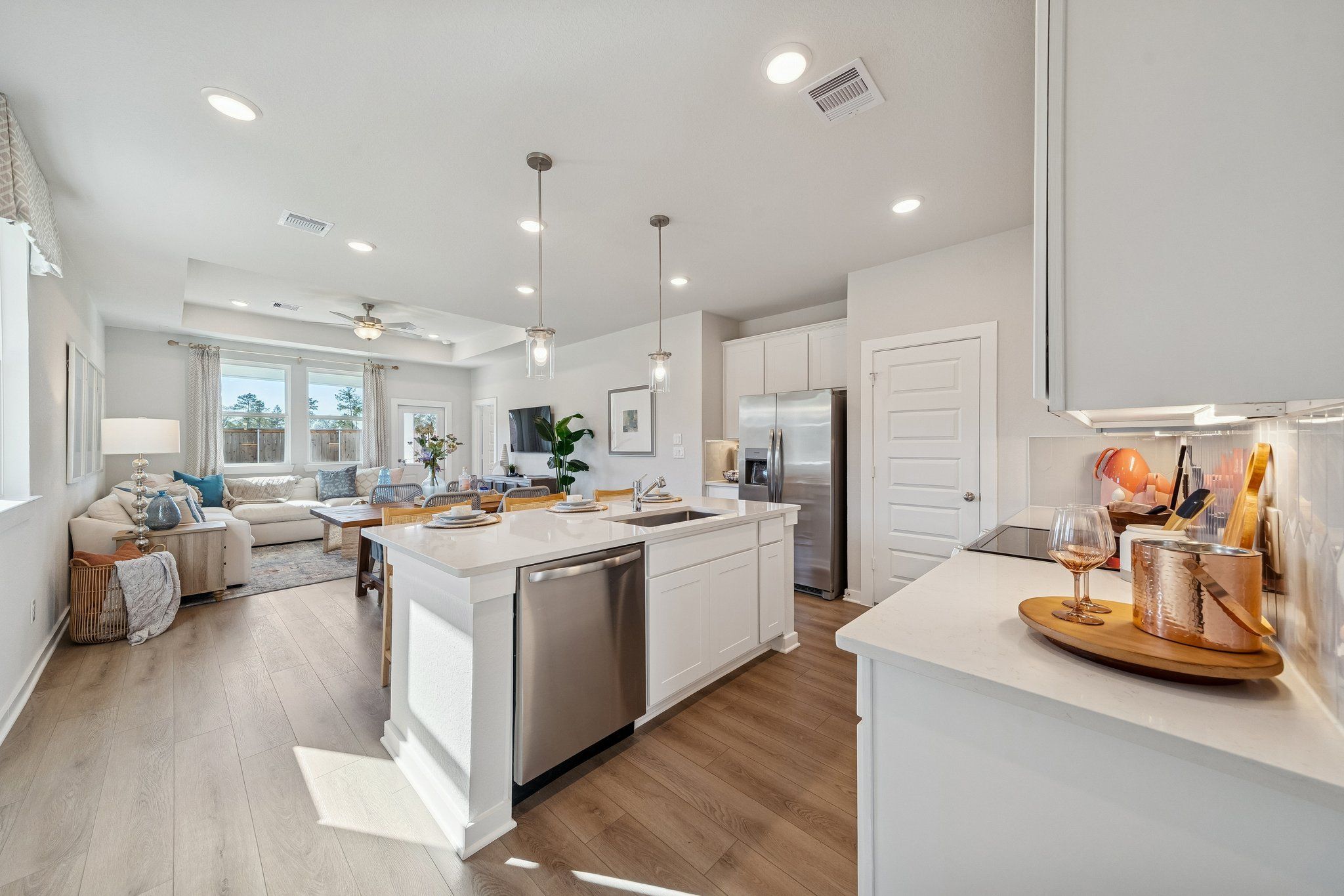 Spacious open-concept kitchen living room at Spring Branch Crossing in Conroe TX with white island hardwood floors and stainless appliances
