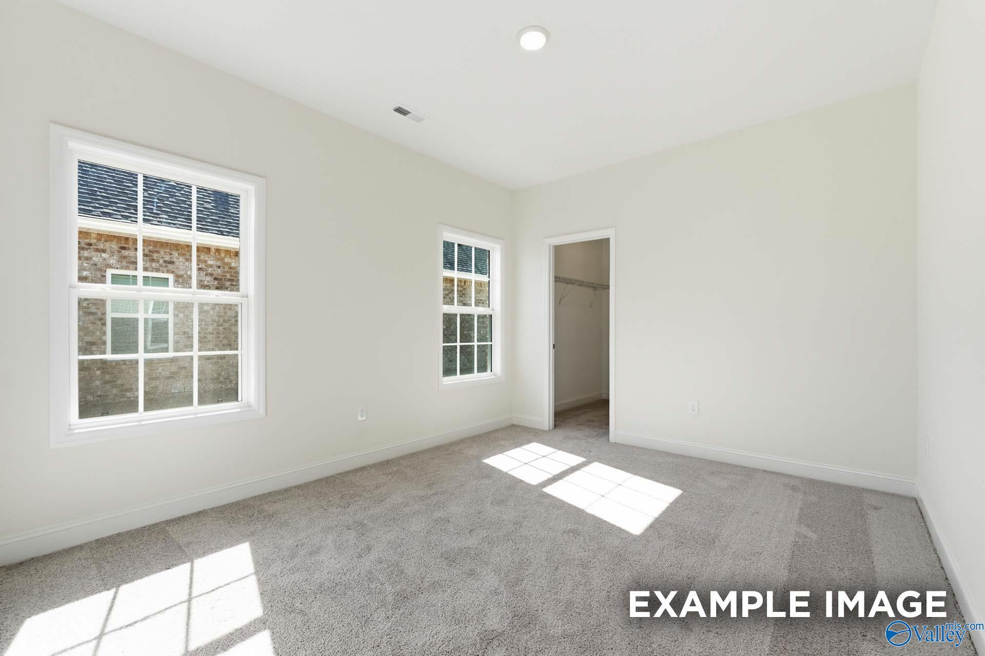 Bright bedroom with plush carpet and walk-in closet in The Valencia floor plan by Davidson Homes in Briercreek.