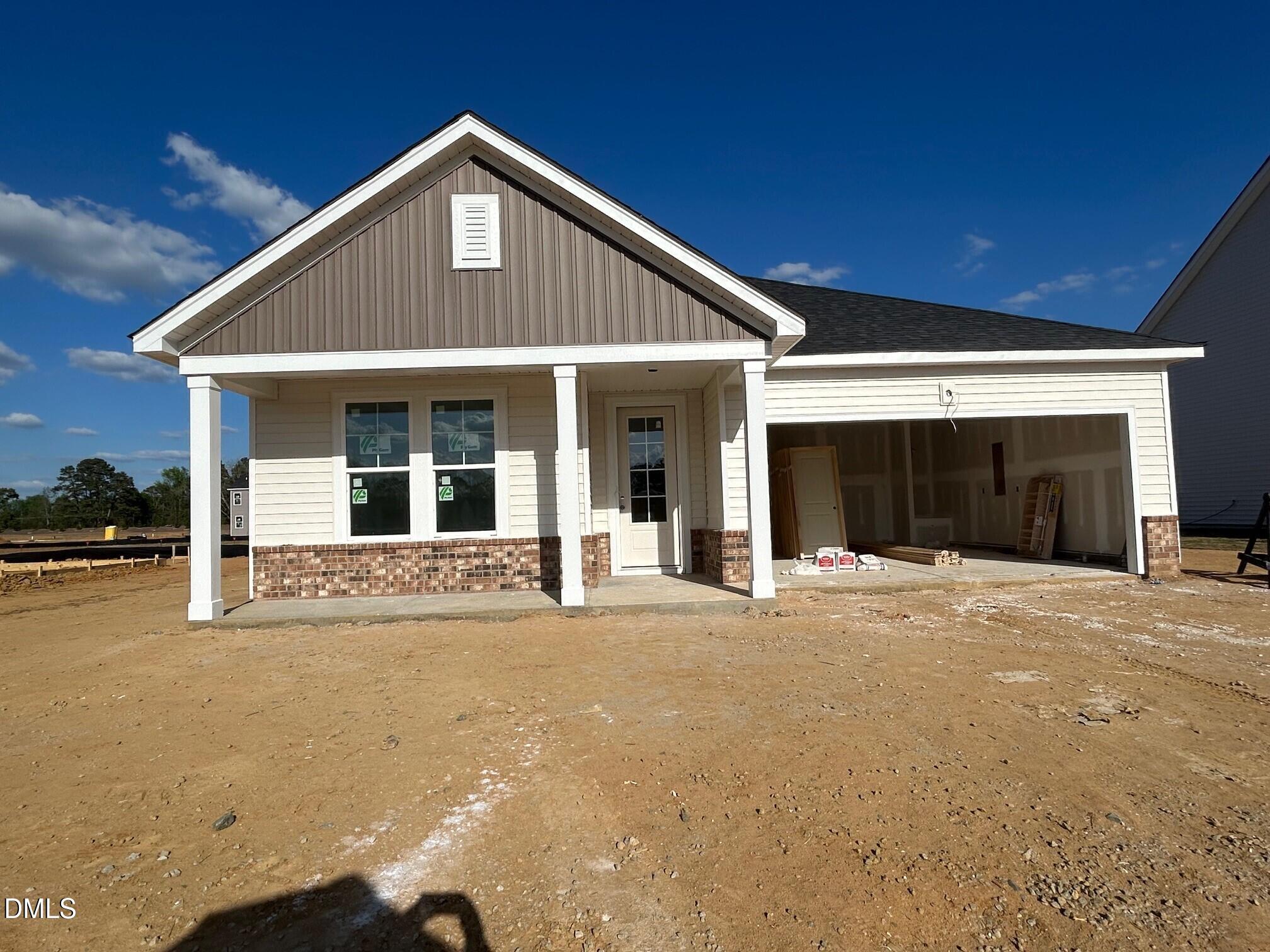 New 3-bedroom ranch home exterior with 2-car garage, covered porch, and brick siding in Retreat at North Main, Lillington, NC