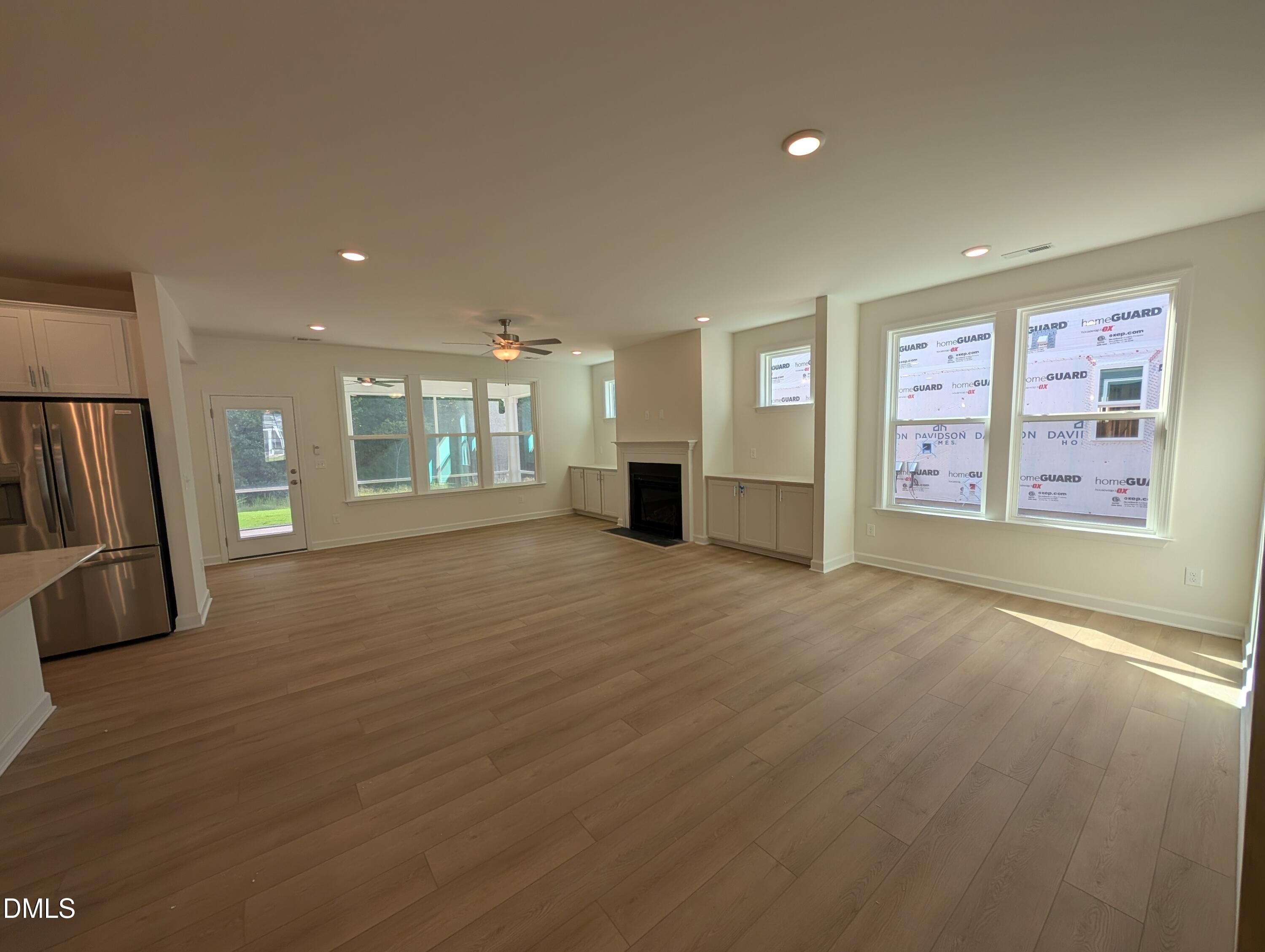 Open-concept great room with hardwood floors, fireplace, and stainless kitchen appliances in Davidson Homes Magnolia A, Wendell NC