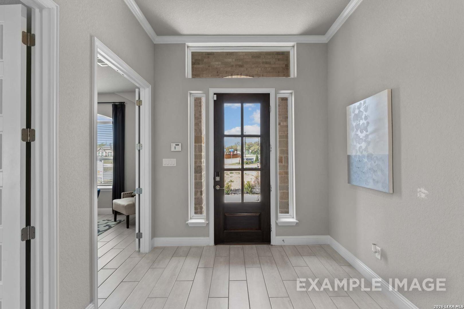 Bright entryway with glass-paneled front door and tile floors in The Garner C floor plan at The Reserve at Potranco Oaks.