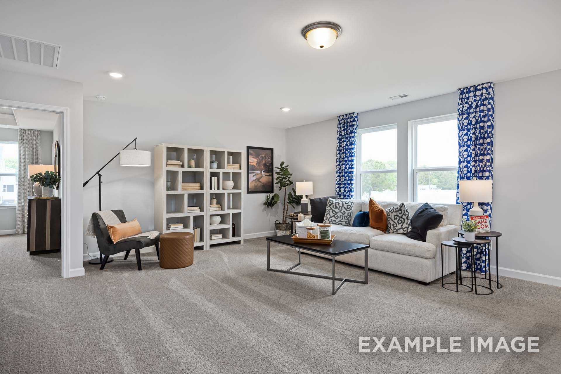 Spacious living room in Adalynn A by Davidson Homes featuring gray sofa, bookshelves, blue curtains, and open layout in Lillington NC