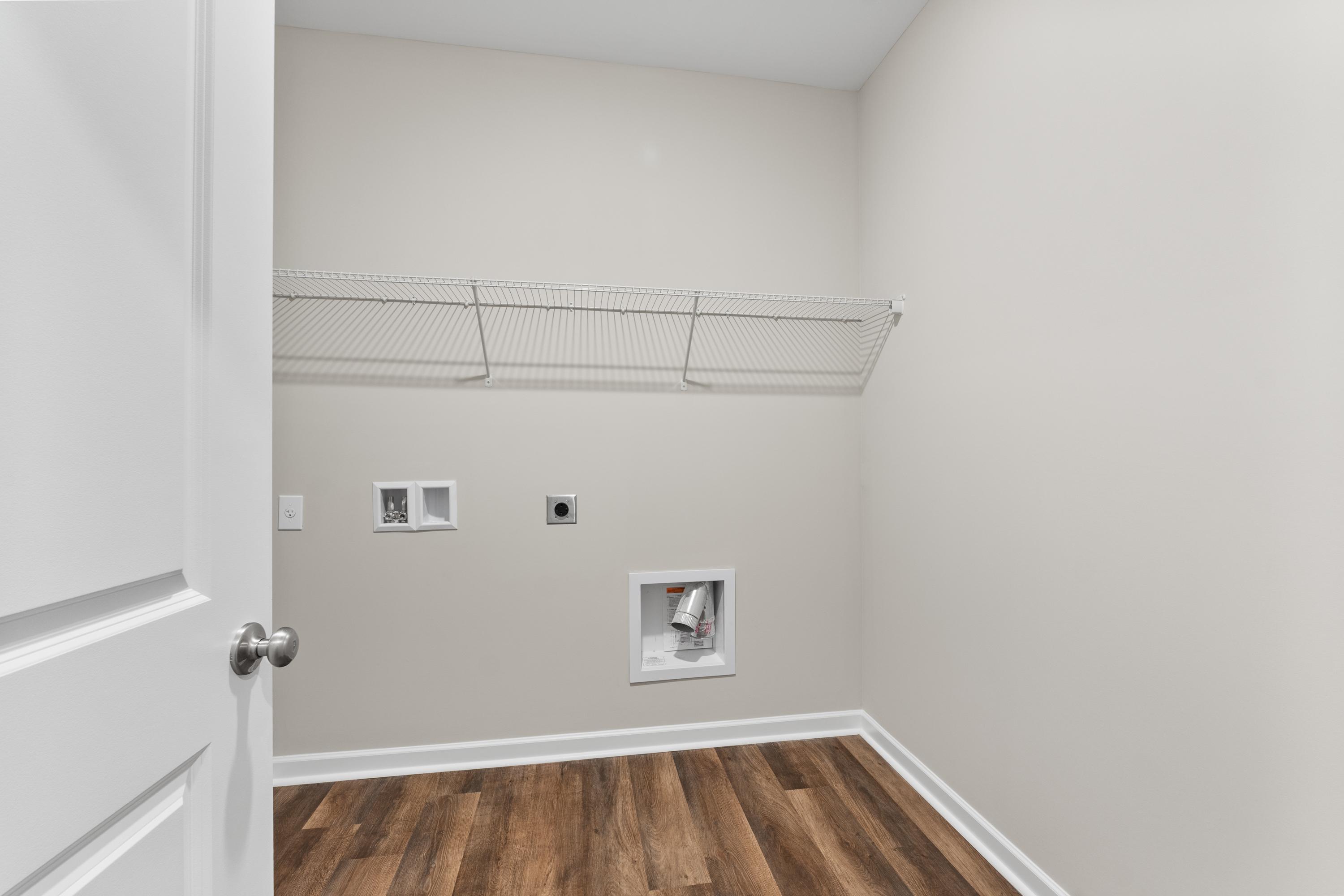 Spacious laundry room in The Haven E by Evermore Homes featuring wire shelving, washer-dryer hookups, and hardwood-style flooring