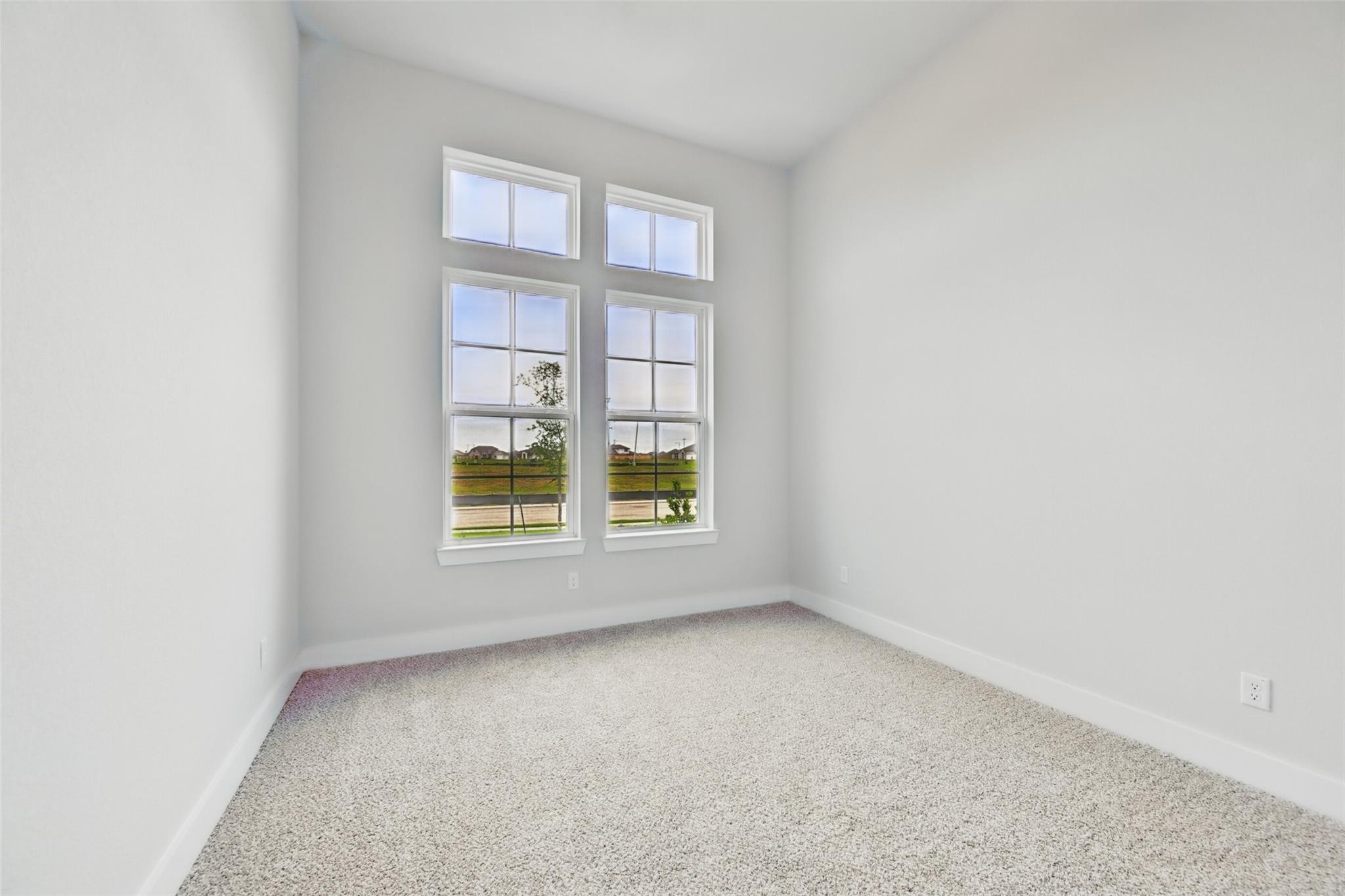Bright empty bedroom with large windows overlooking green fields in Davidson Homes The Victoria C, Lago Mar, Texas City, Texas