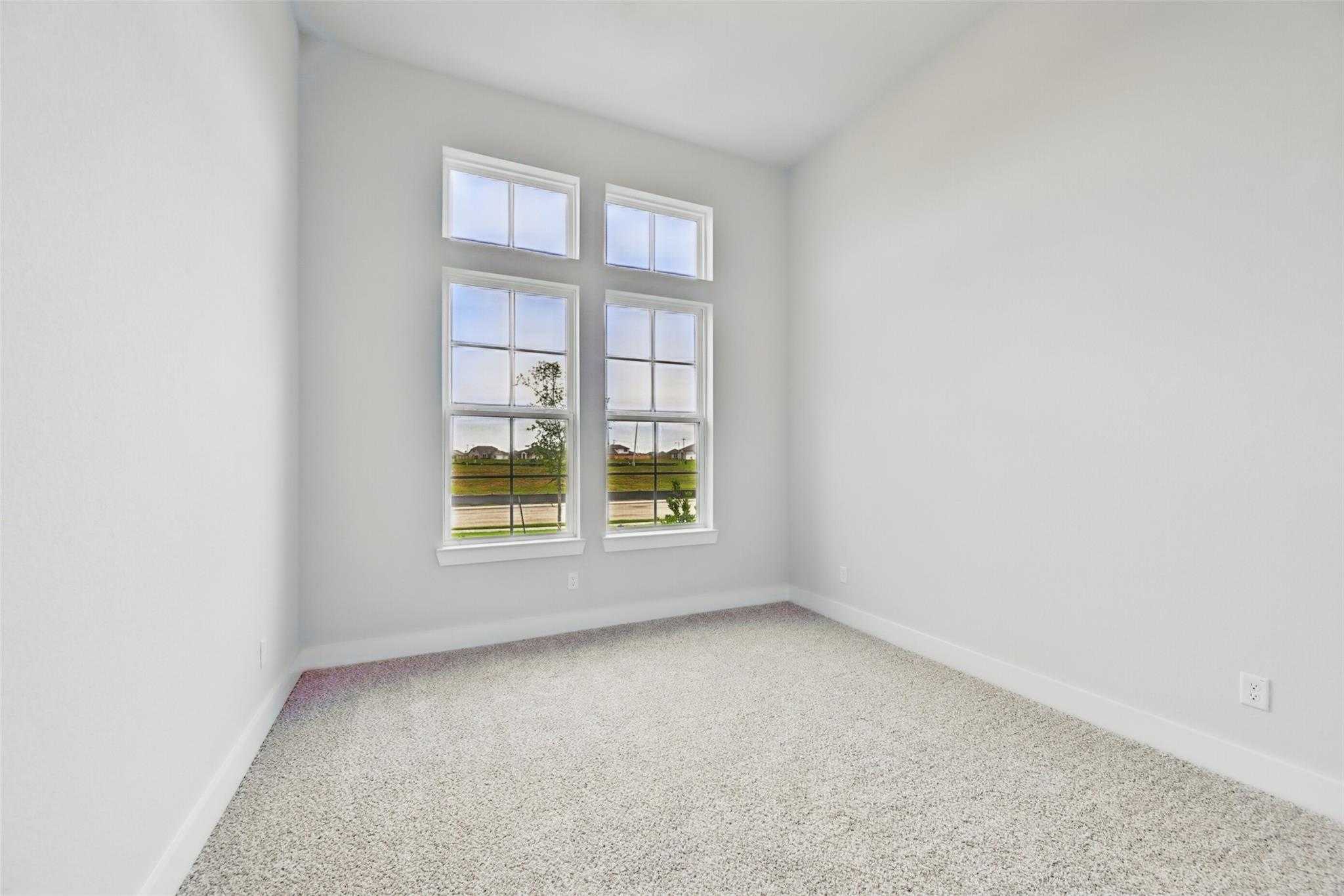Bright empty bedroom with large windows overlooking green landscape in Davidson Homes The Victoria C, Lago Mar Texas City