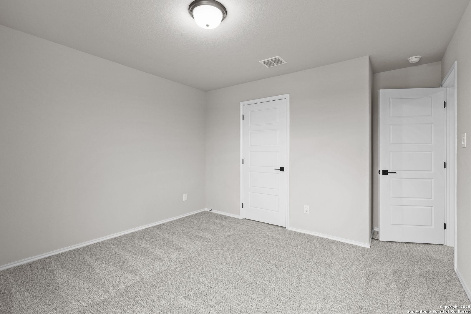 Empty secondary bedroom featuring gray walls, carpeted floor, and two white doors in Davidson Homes The Murray J, San Antonio, Texas