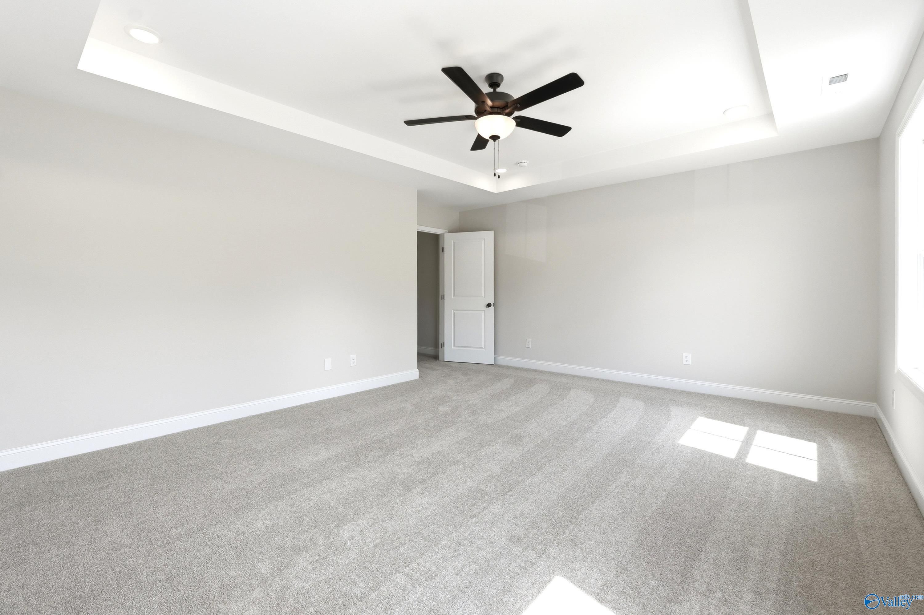 Spacious bedroom with tray ceiling and ceiling fan in The Russell A floor plan by Davidson Homes in Huntsville, Alabama.