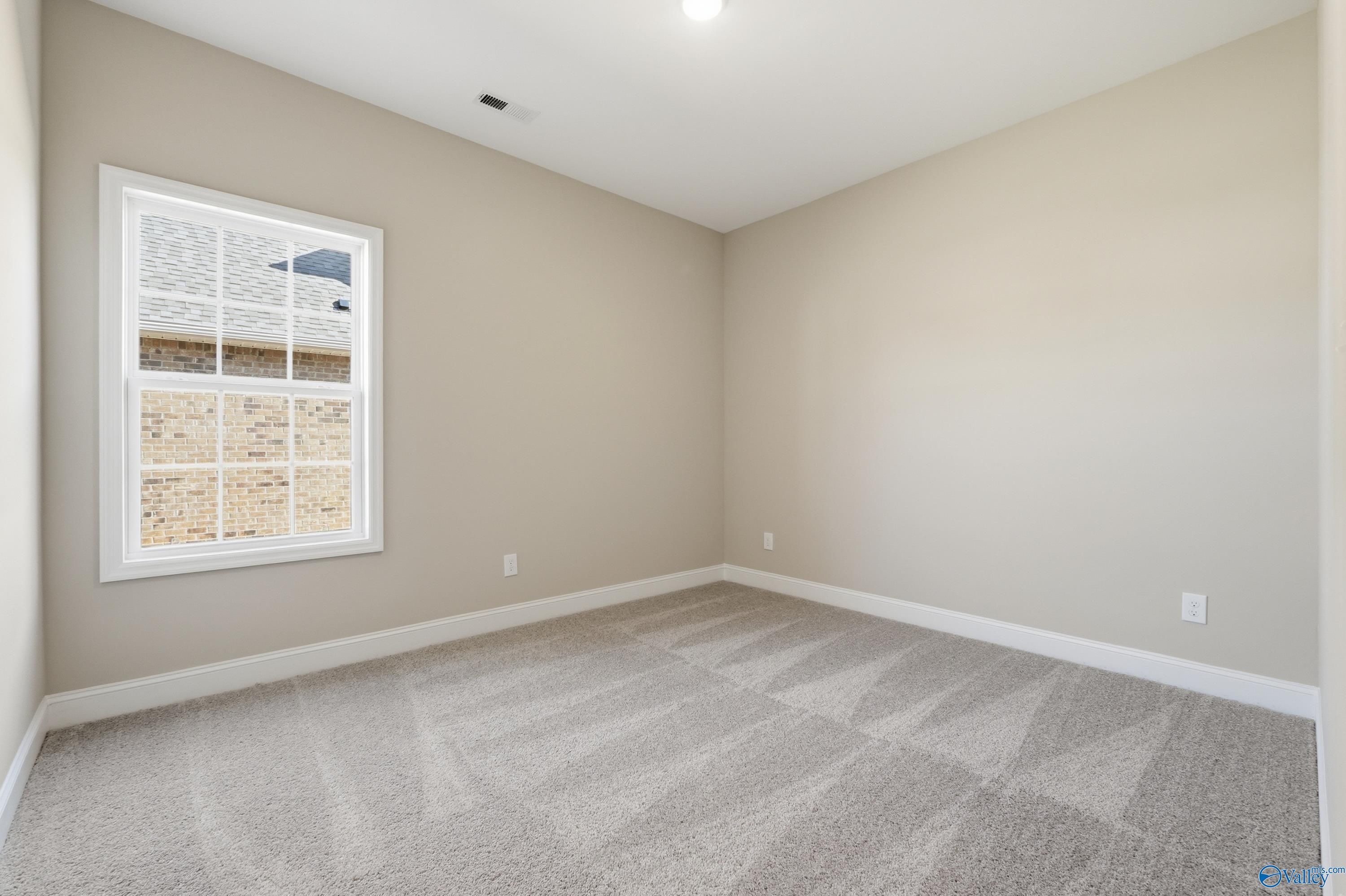Bright secondary bedroom with beige walls, large window, and carpeted floor in Davidson Homes The Rockford, Creekside, Harvest, AL