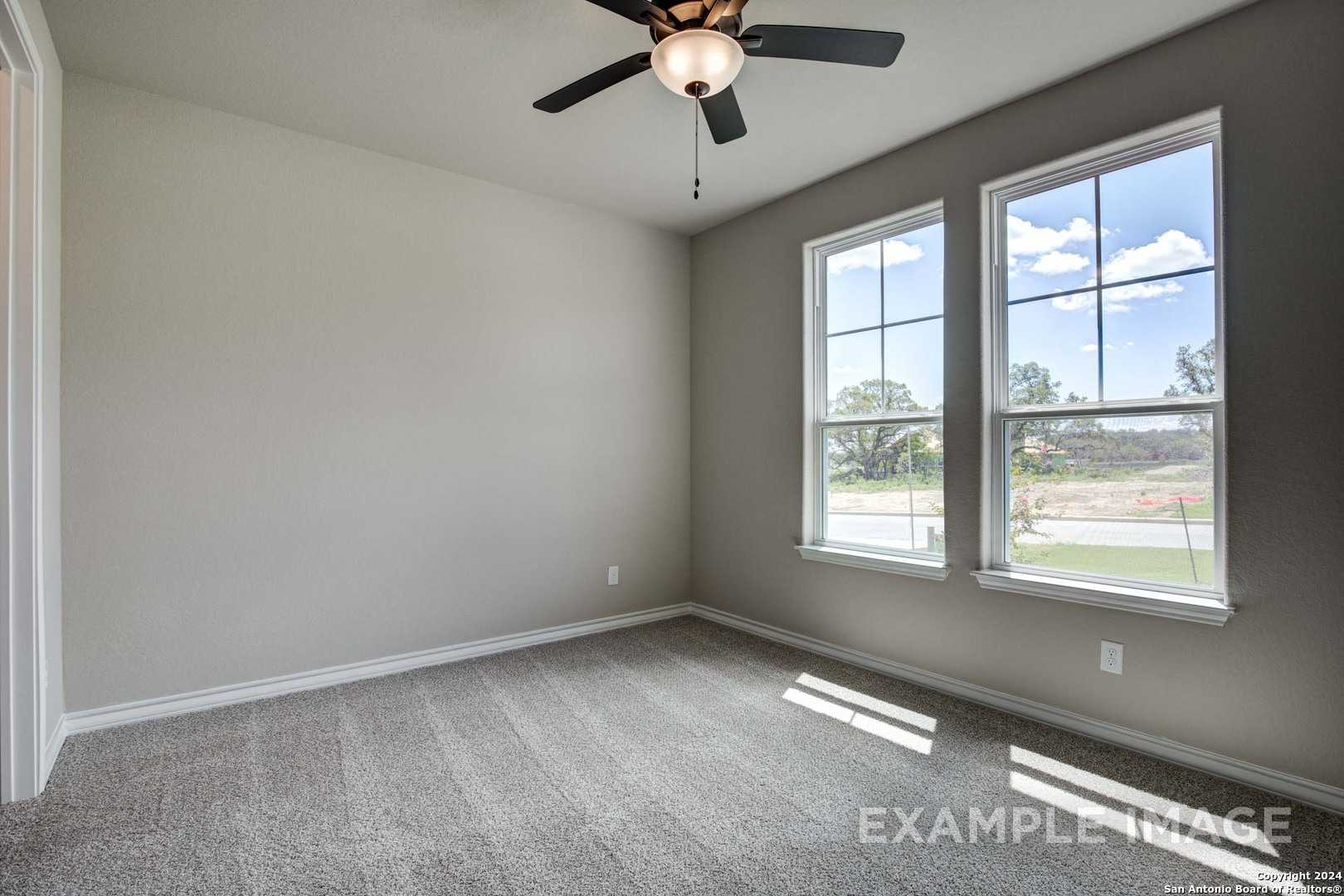 Sunlit secondary bedroom with gray walls, carpet flooring, ceiling fan, and large windows in Davidson Homes The Rockford G, Ladera, San Antonio