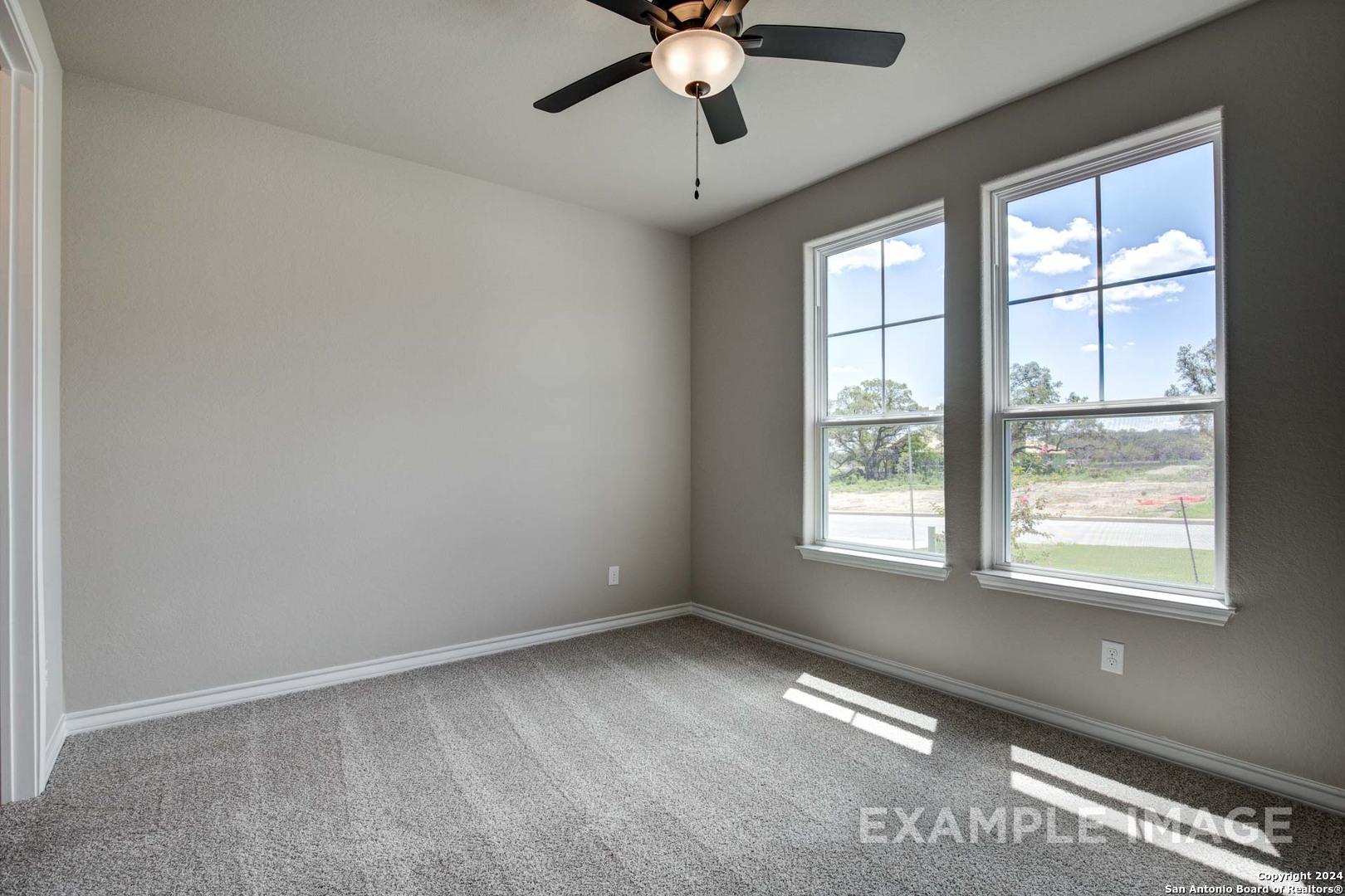 Sunlit secondary bedroom with gray walls, carpet flooring, ceiling fan, and large windows in Davidson Homes The Rockford G, Ladera, San Antonio