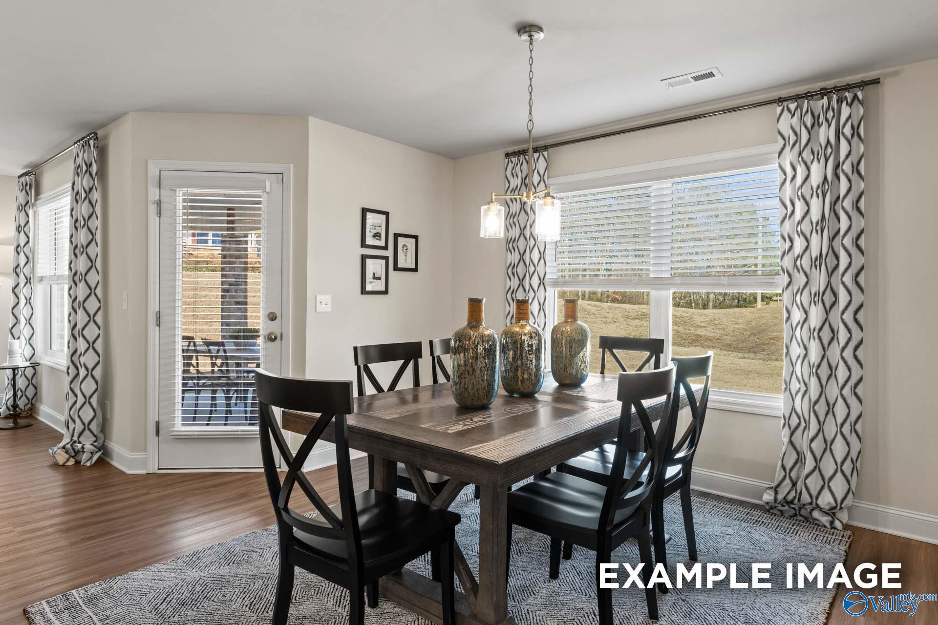 Elegant dining room with wooden table, black chairs, chandelier, and patio views in The Franklin C, Davidson Homes, New Market, Alabama