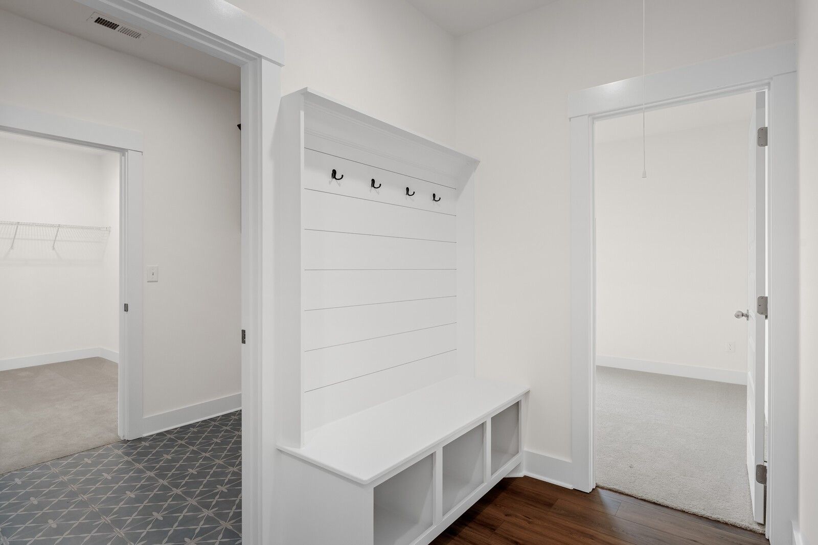 Built-in white mudroom bench with coat hooks in The Prairie C floor plan at Woods Crossing, Gallatin, Tennessee.